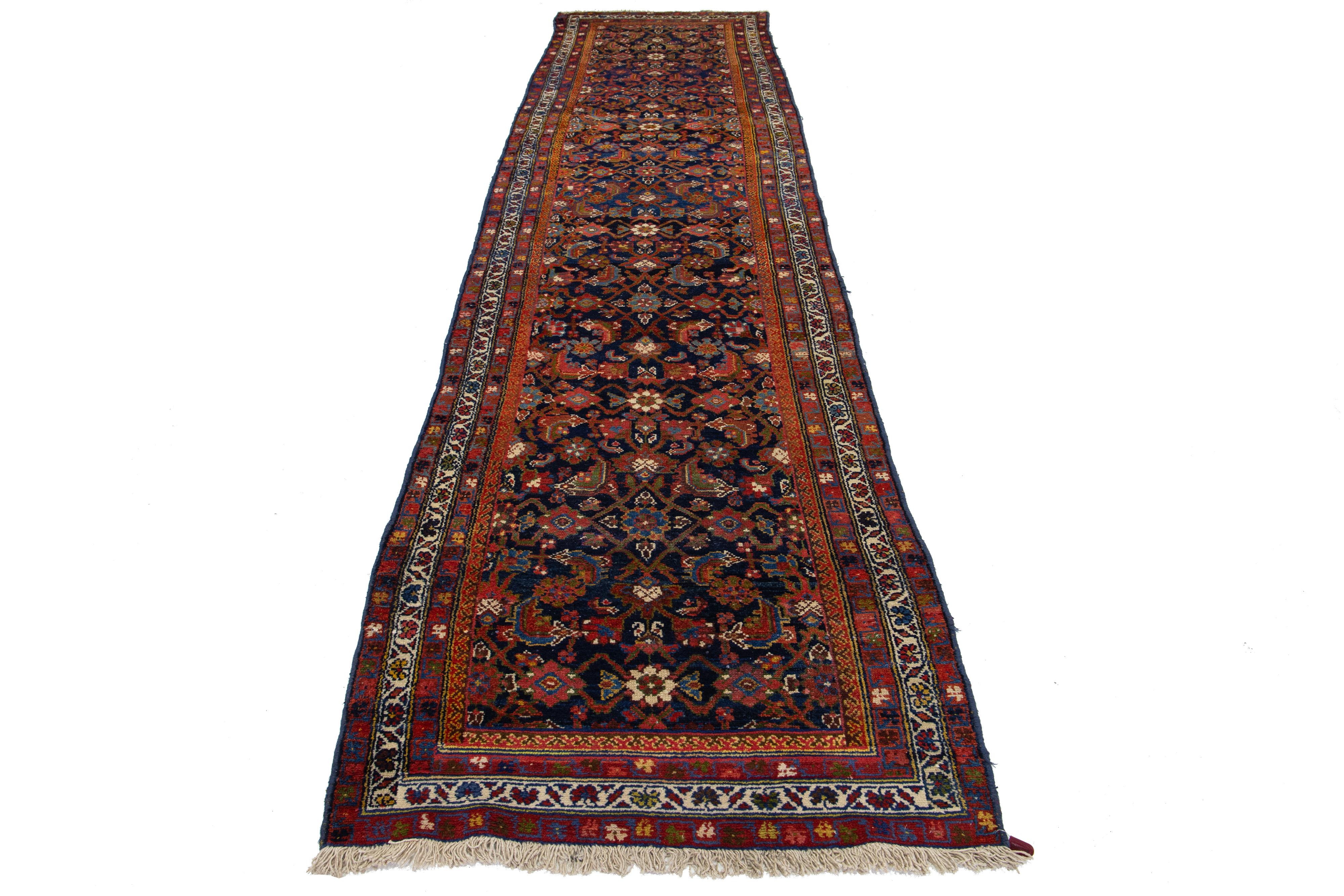 Ce tapis persan en laine de Malayer, fait à la main, date du 20e siècle. Il présente un champ bleu marine avec des accents rouille, jaunes, bleus et verts.

Ce tapis mesure 3'6'' x 14'3''.

.