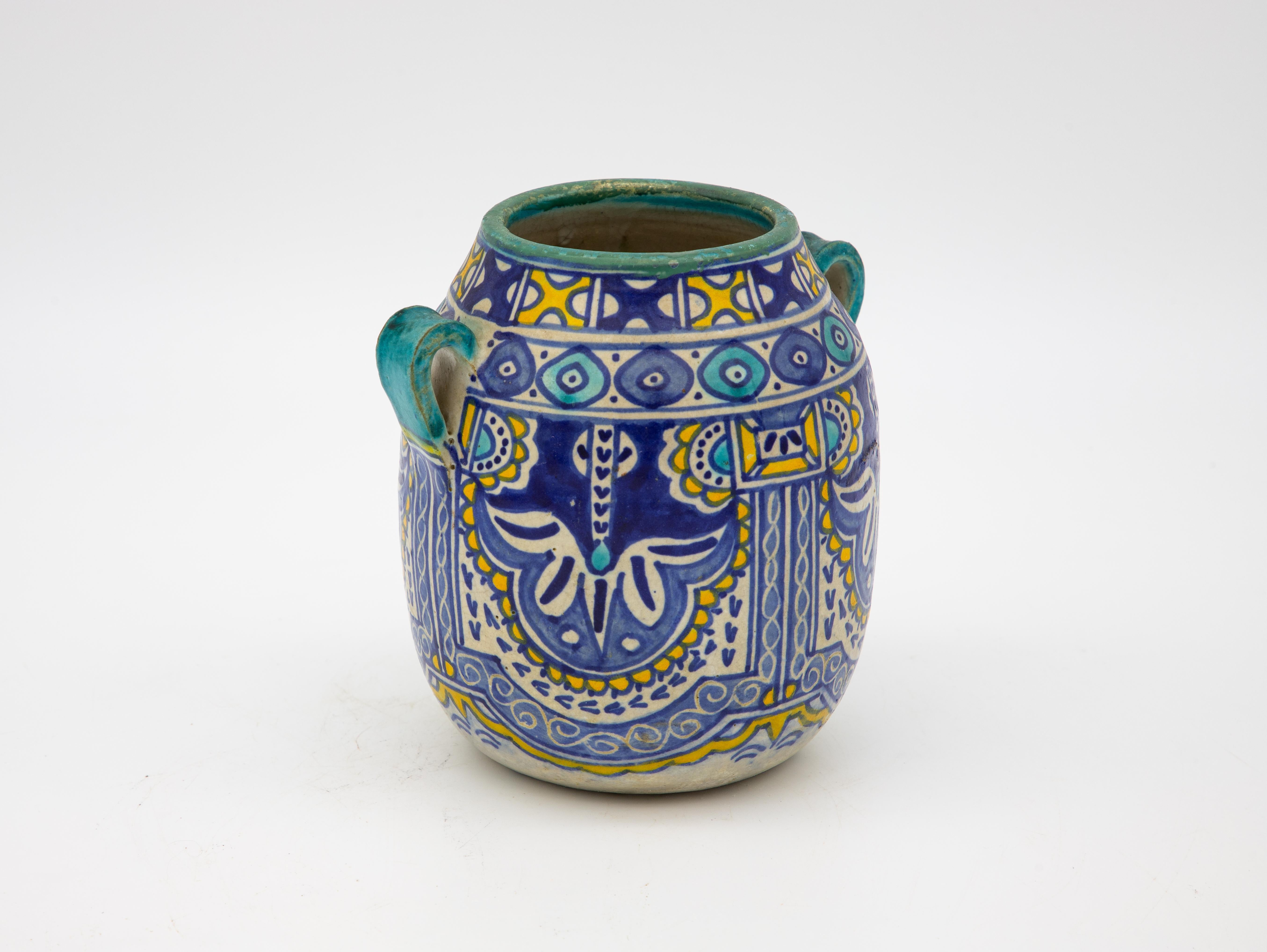 An early 20th century vase from Fes, Morocco. Typical bright colors of cobalt, turquoise, and saffron. Two handles and an open mouth. Wear consistent with age and use.