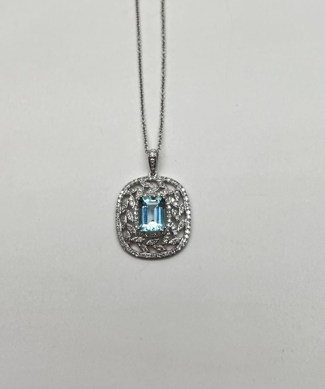 A captivating pendant necklace featuring a central rectangular blue Aquamarine encased in an intricate lattice of sparkling diamonds. The pendant is suspended from a delicate chain, showcasing meticulous craftsmanship. 14K White Gold. 0.54 CTW
