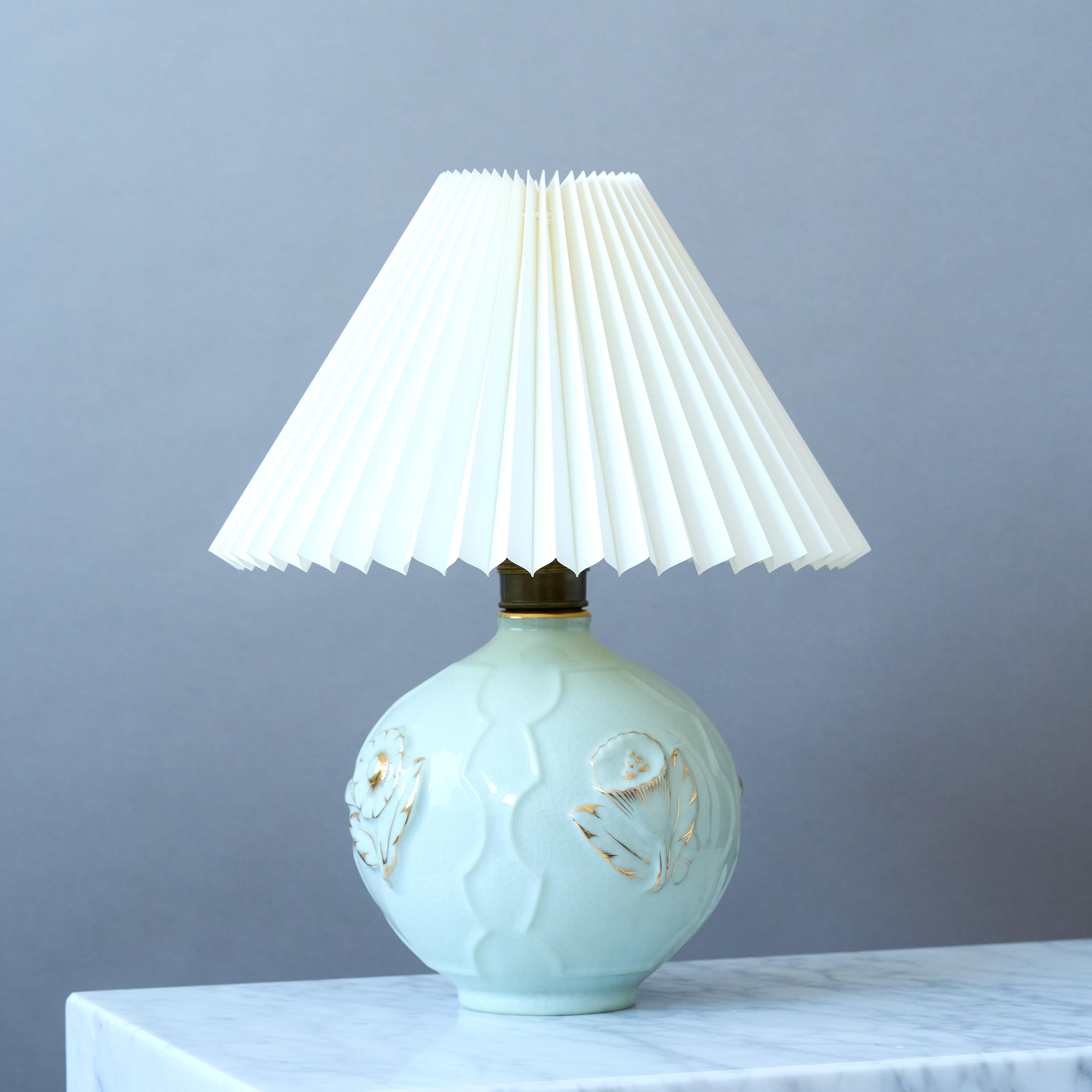A stunning stoneware Swedish Grace / Art Deco table lamp. Amazing relief decor with hand-painted details in gold.

Attributed to Tyra Lundgren. This model was produced in the 1920s by both the factories ALP (Lidköpings Porslinsfabrik) in Sweden and