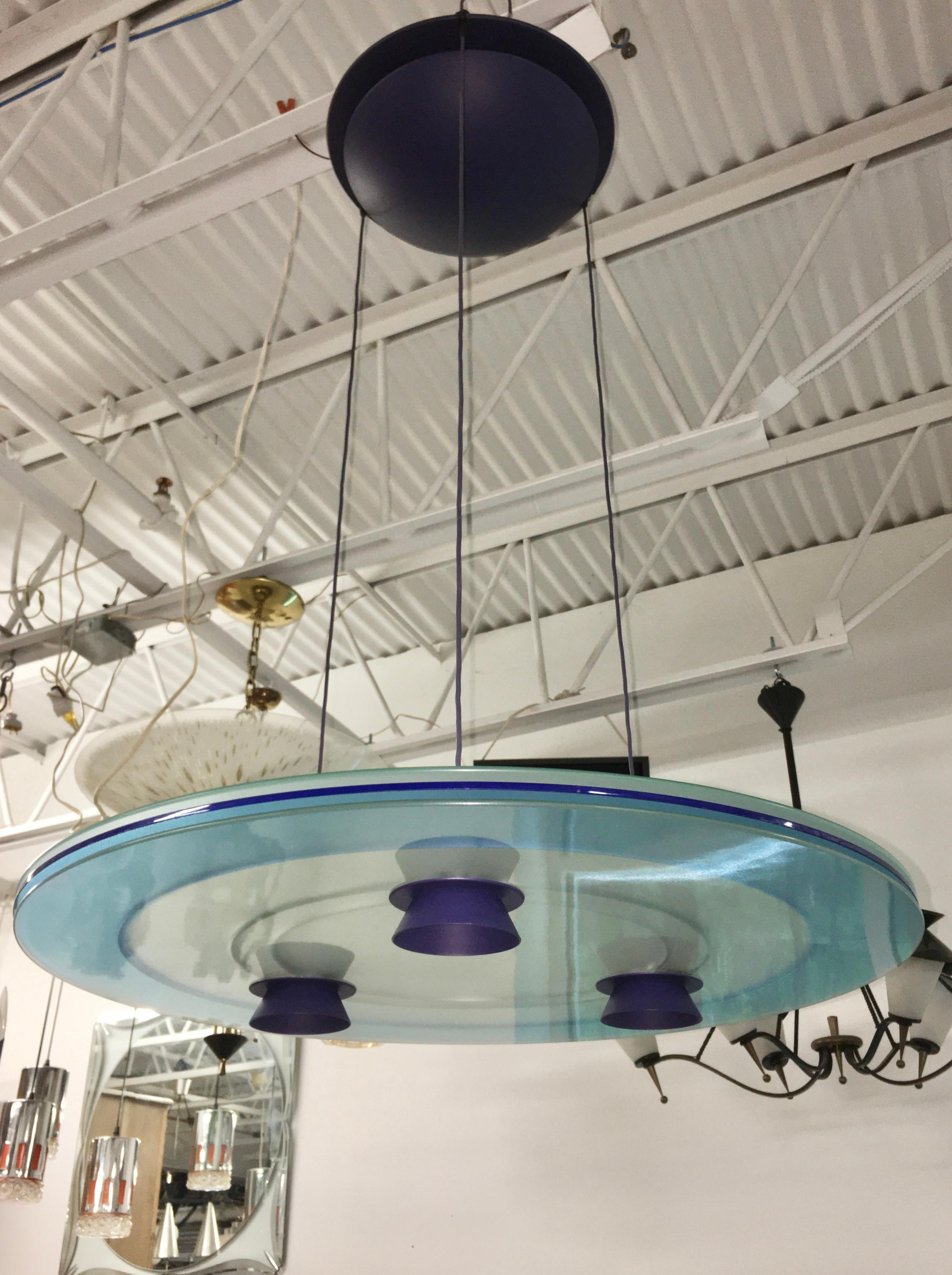 Blue Aurora pendant.
Perry King and Santiago Miranda designed the 'Aurora' pendant light for Arteluce, by then a division of Flos.
The Aurora provides direct and diffused light with three 50 W halogen spotlights from a suspended disk comprised of a