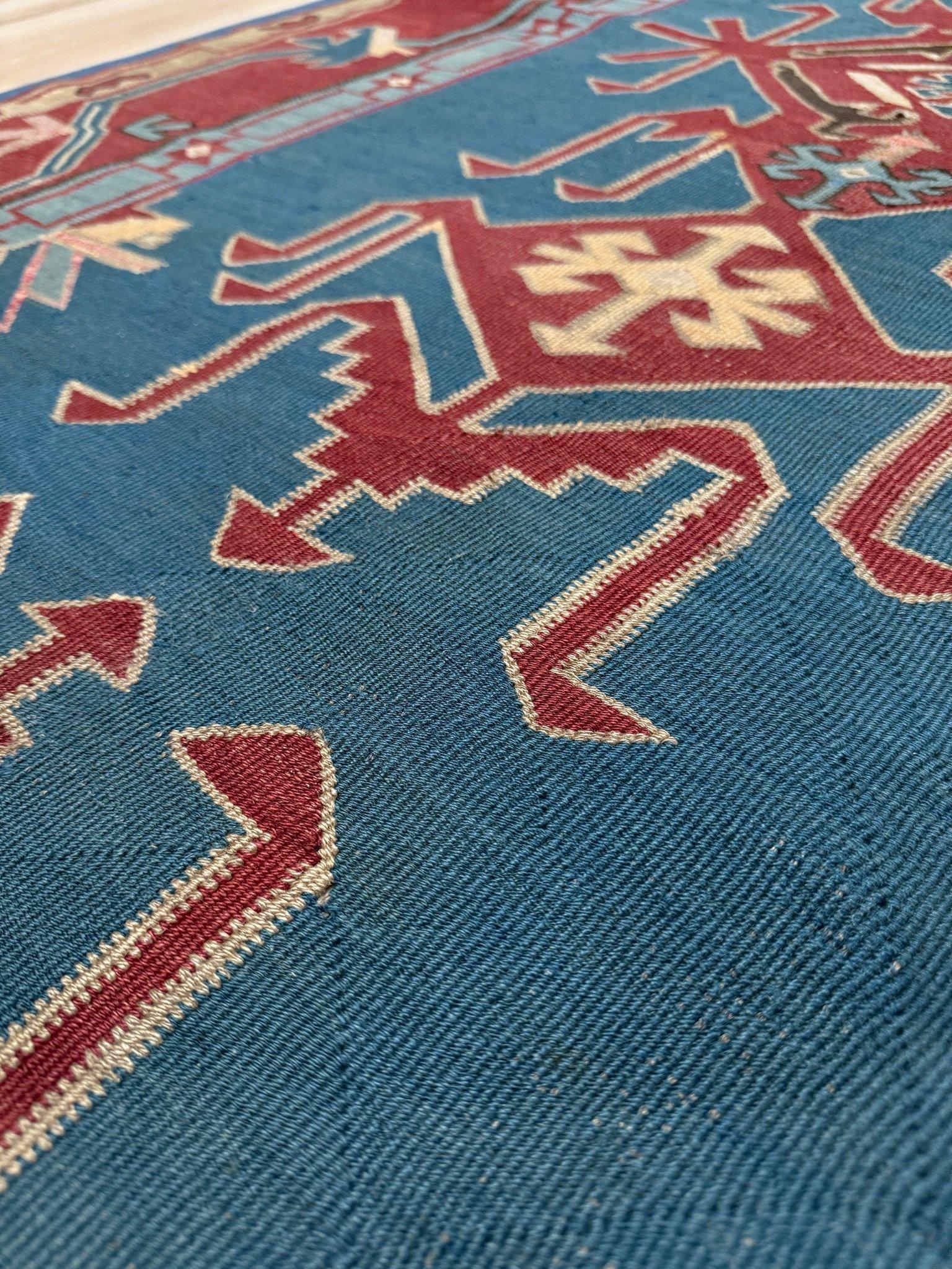 Ce kilim vintage A du Caucase est un véritable drame en laine - des motifs tribaux audacieux s'étendent sur une mer de bleu denim, encadrés par un rouge terracotta et des tons doux de pistache. Tissé à la main avec un soin méticuleux, sa texture à