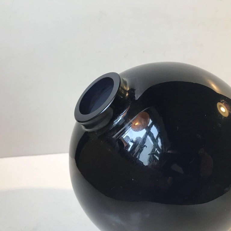 A rocking globe-shaped cobalt blue glass vase designed by Birgitta Watz in 1995 and manufactured by Lindshammar in Sweden. Standing on a plane surface this vase will rock from side to side without losing its balance. The gold plated stand will come