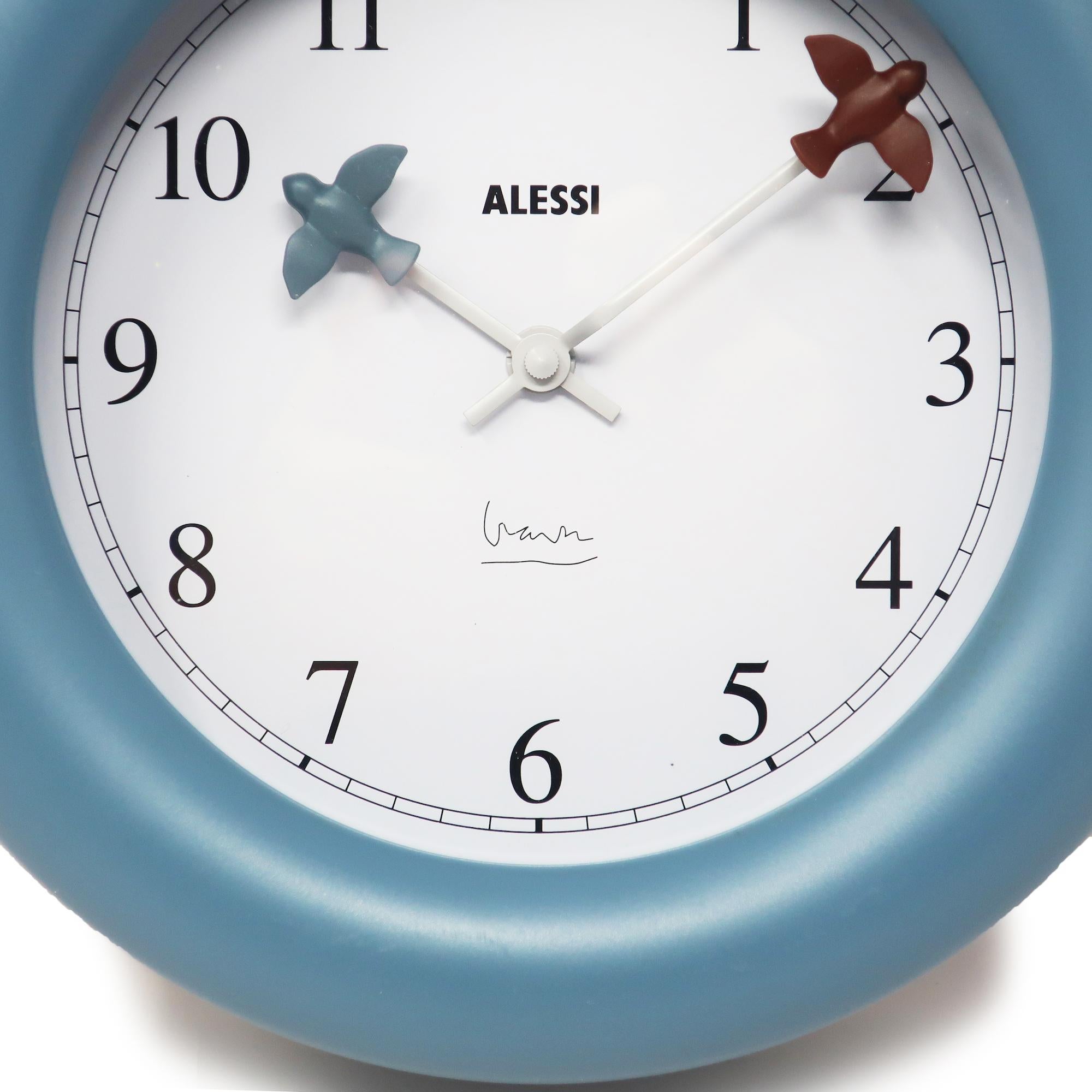 This 1992 design wall clock by Michael Graves is one of Alessi's most successful designs, along with Graves’ stainless steel 9093 kettle.  The clock had a unusually deep blue plastic body, a white face, black numbers, and blue and maroon birds at
