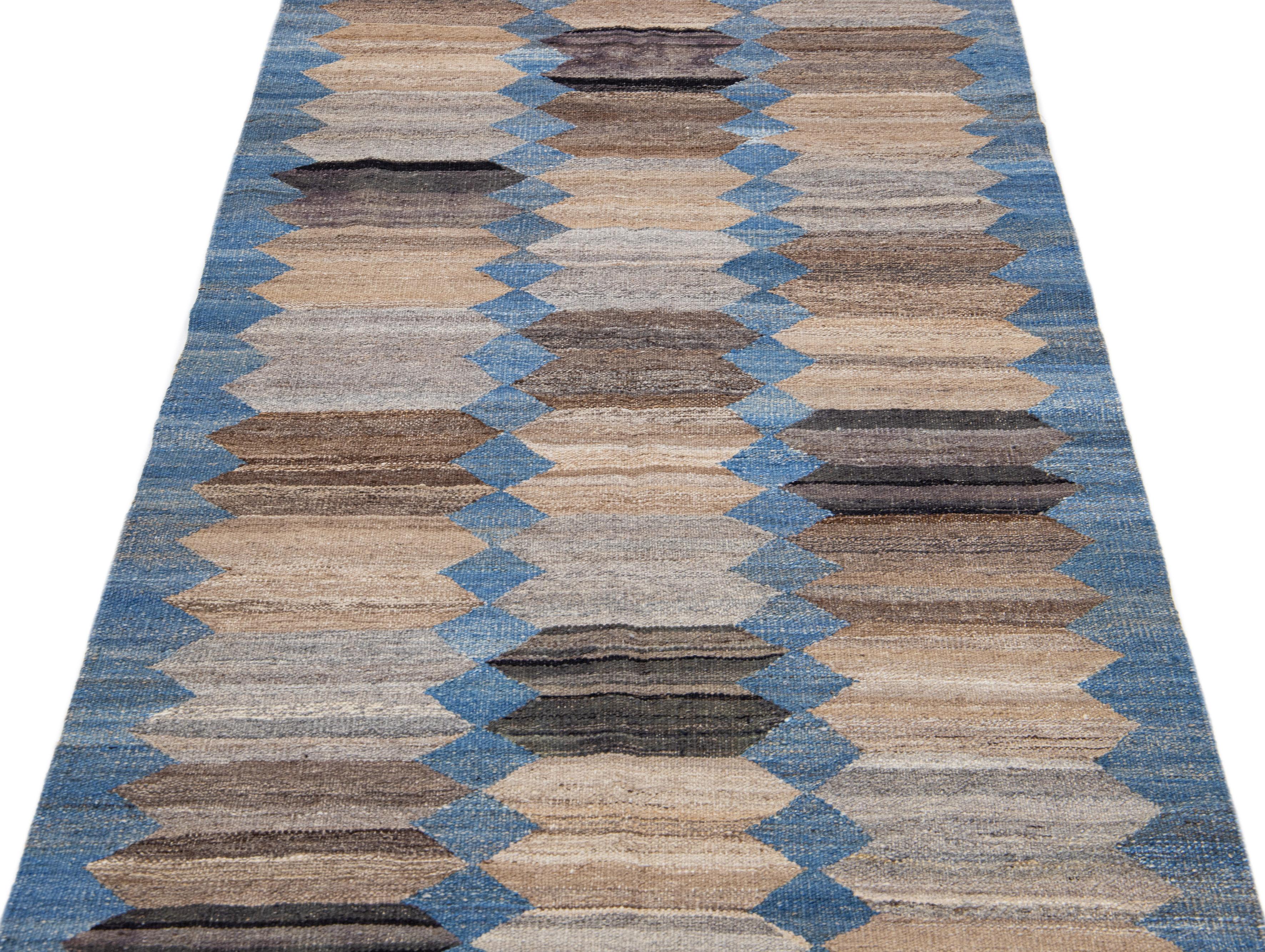 This Deco flatweave wool runner exhibits a captivating blue field with brown and beige accents, creating a contemporary and aesthetically-pleasing abstract design. The natural material of the Deco wool rug is designed for comfort and long-lasting