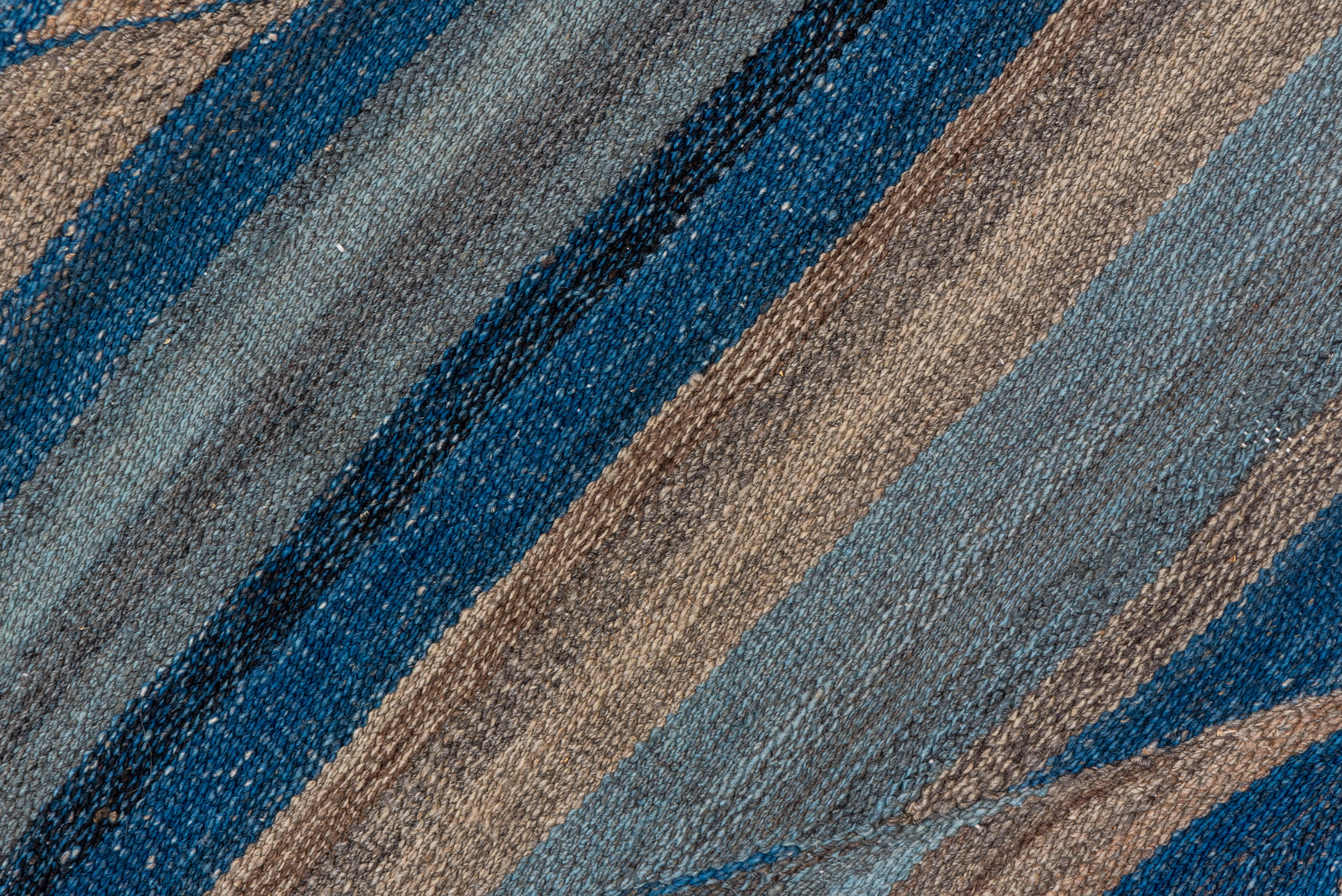 A modern flatweave with a wave-like pattern in tones of blue, light blue and brown. Woven in Afghanistan.