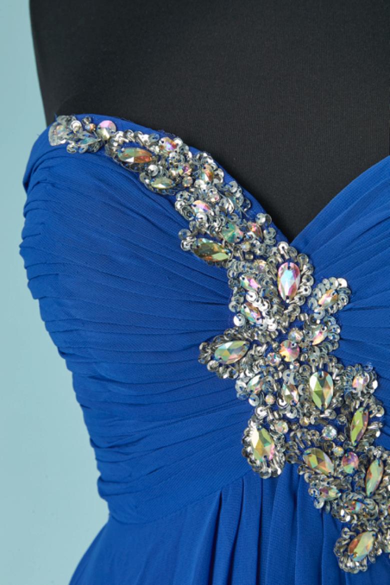 Robe de soirée bleue à bustier, ornée de strass. Composition du tissu principal et doublure : polyester. 
Bande de silicone à l'intérieur du bustier sur le bord supérieur. Bustier désossé et soutien-gorge paddé. Fermeture à glissière et crochet au