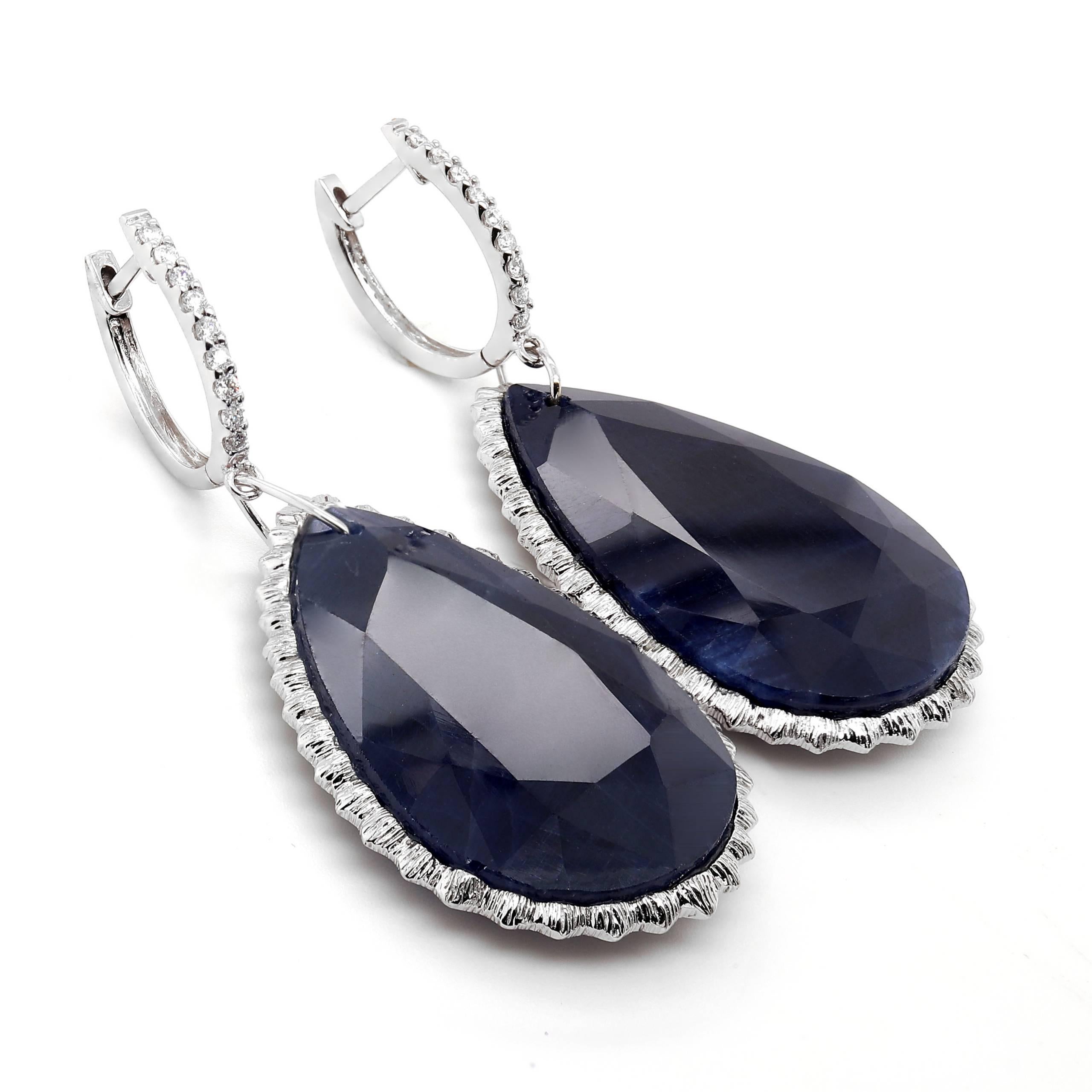 Dangle earrings with 2 blue cabochon pear shape Sapphires of about 77.21 carats. Sapphires are surrounded by 18 round brilliant cut Diamonds of about 0.14 carats with a clarity of SI and color H. All stones are set in 18k white gold. The total