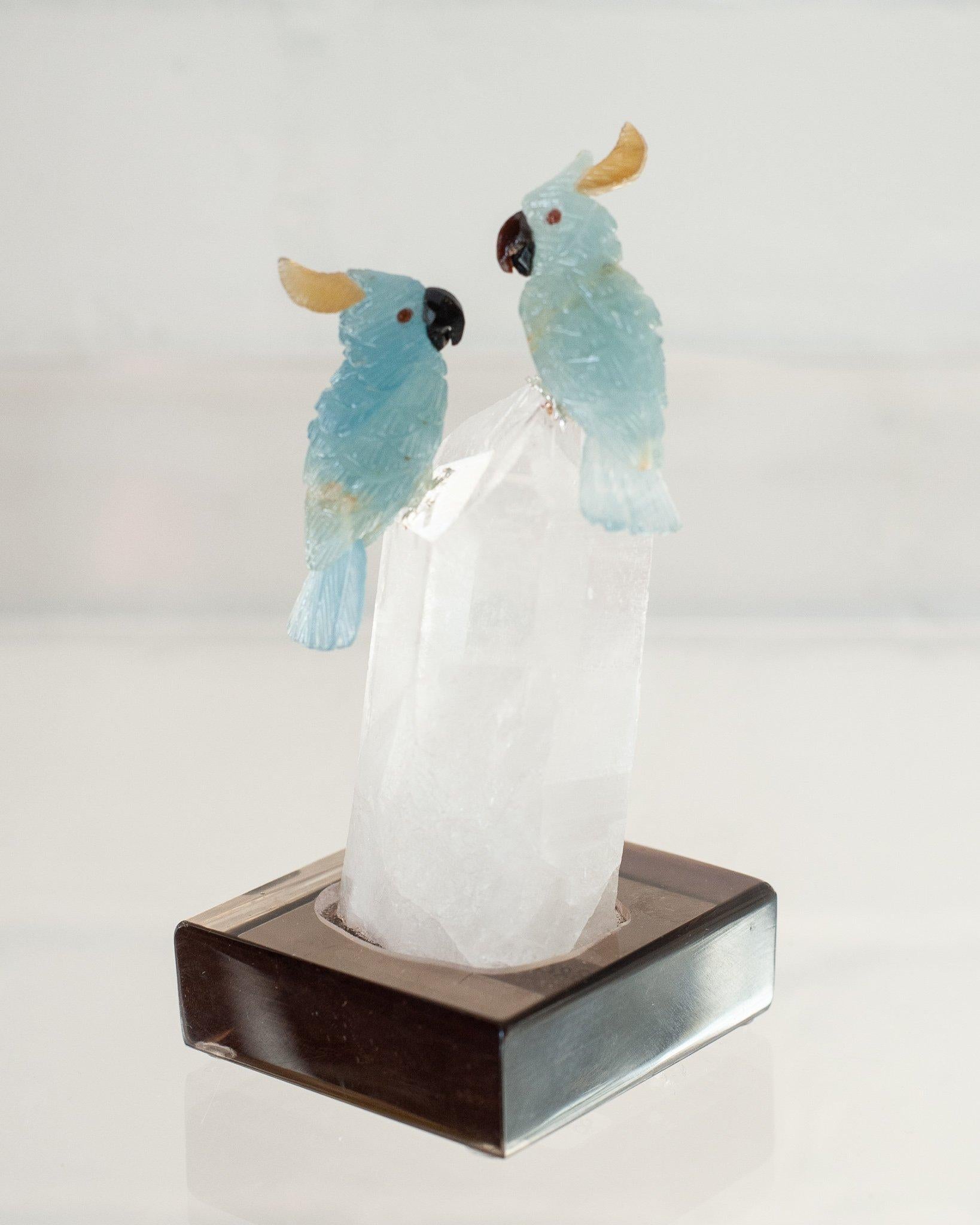 A beautiful hand carved semi precious blue calcite lovebird pair mounted on a clear quartz point mineral specimen base. These exotic birds are a decorative combination of ornithology and geology.