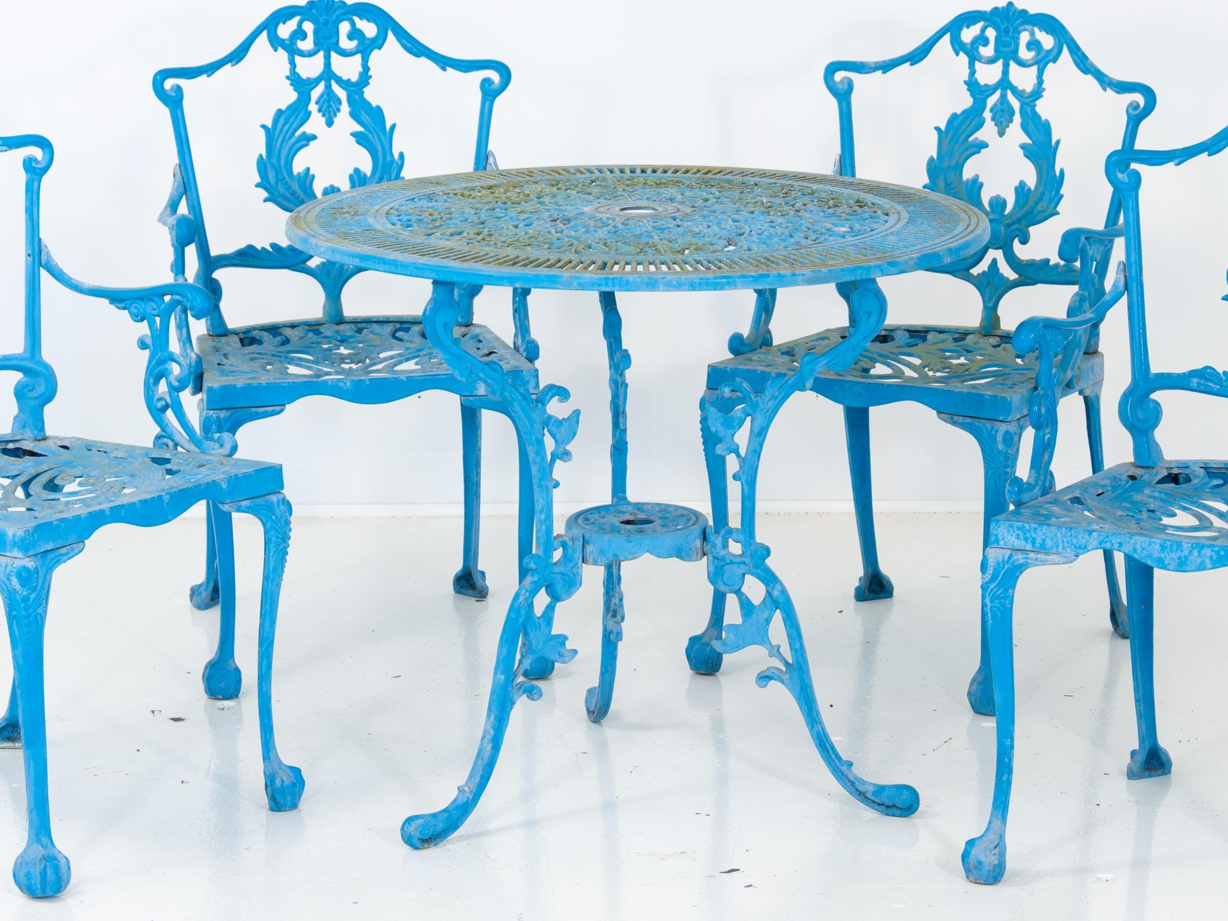 A Victorian style English garden dining table and four armchairs with an acanthus motif. A bright and beautiful blue color finished the table and chairs made of cast metal alloy. Mid 20th century. Measurements are as follows:
Table diameter-
