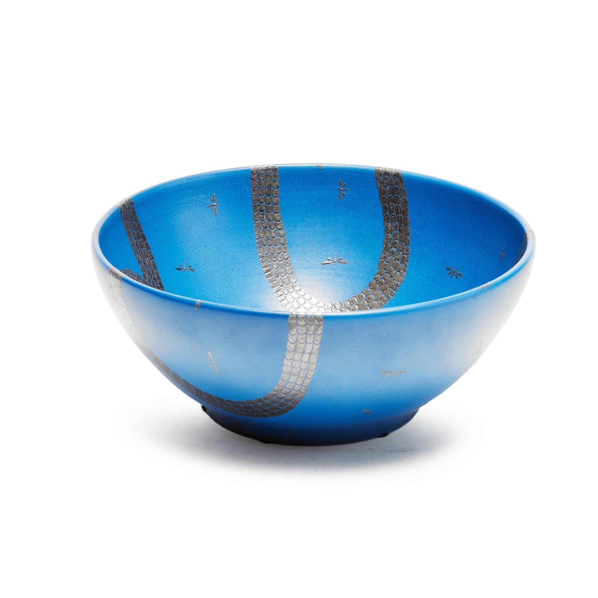 Un bol en céramique bleue signé avec des libellules et des serpents incrustés d'argent.