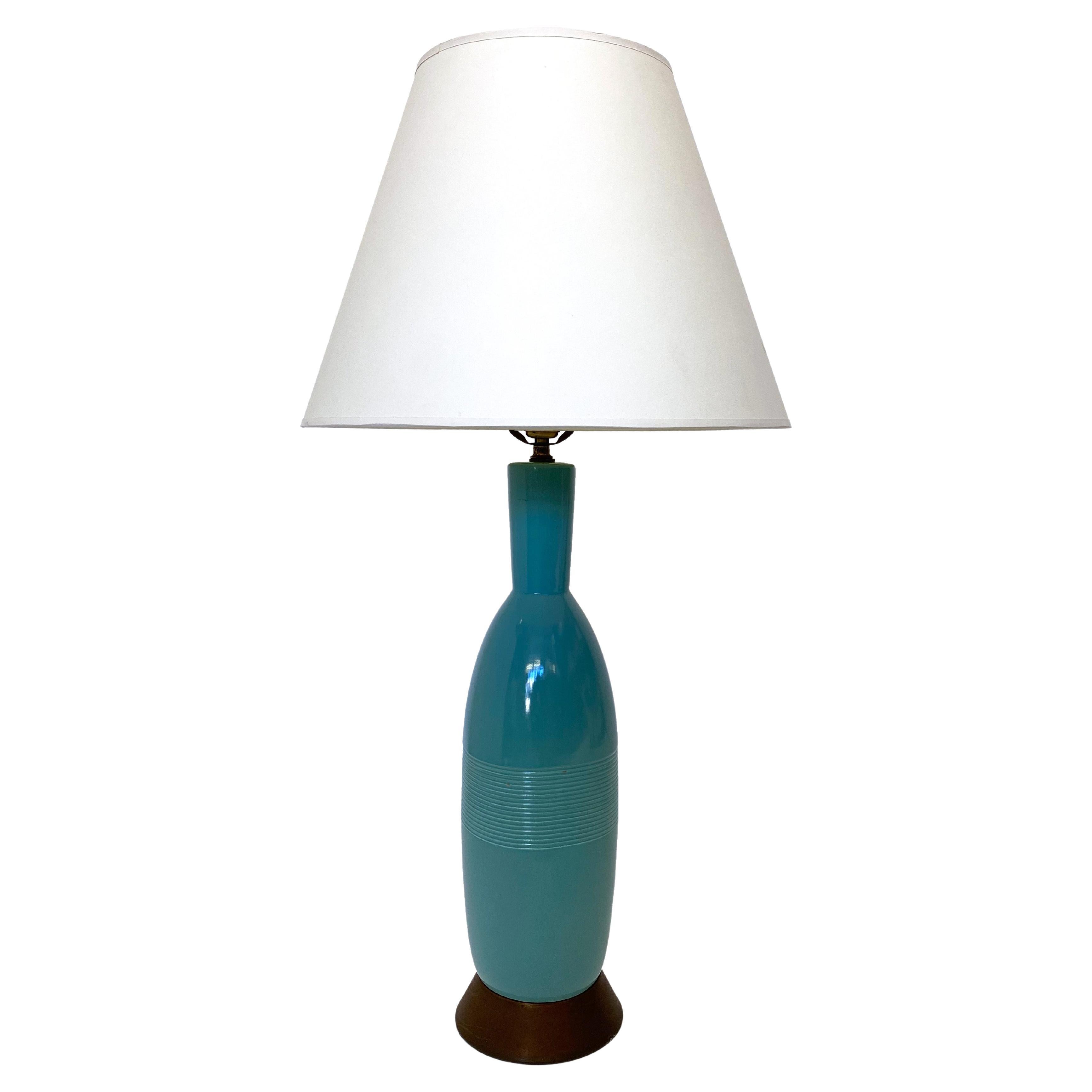 Blue ceramic table lamp with metal base. This ceramic piece has a unique bottle like shape that is enhanced with a striped pattern detail in the middle of the body. 

Property from esteemed interior designer Juan Montoya. Juan Montoya is one of
