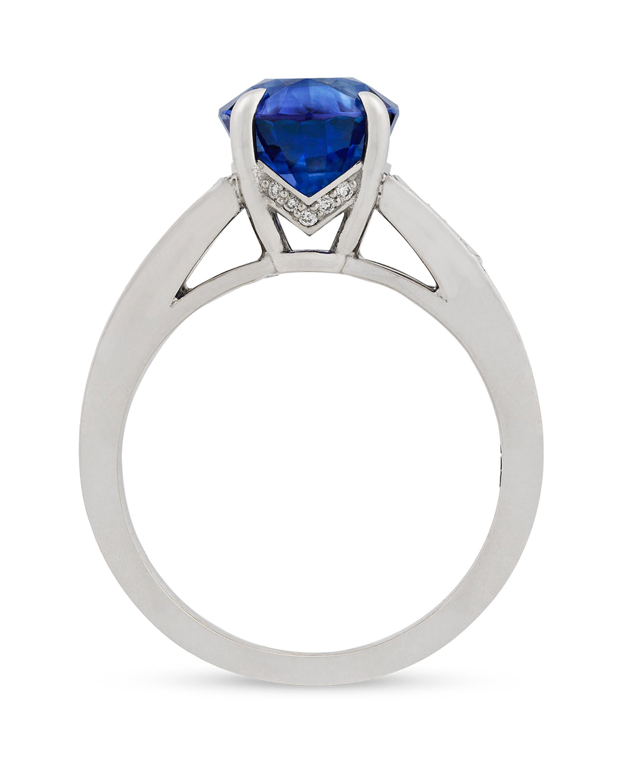 This brilliant 4.15-carat oval-shaped blue Ceylon sapphire is enhanced by two shield-cut white diamonds totaling 0.28 carat. The richly colored stone is showcased in a classic 18K white gold setting encrusted with 58 round diamonds totaling 0.18
