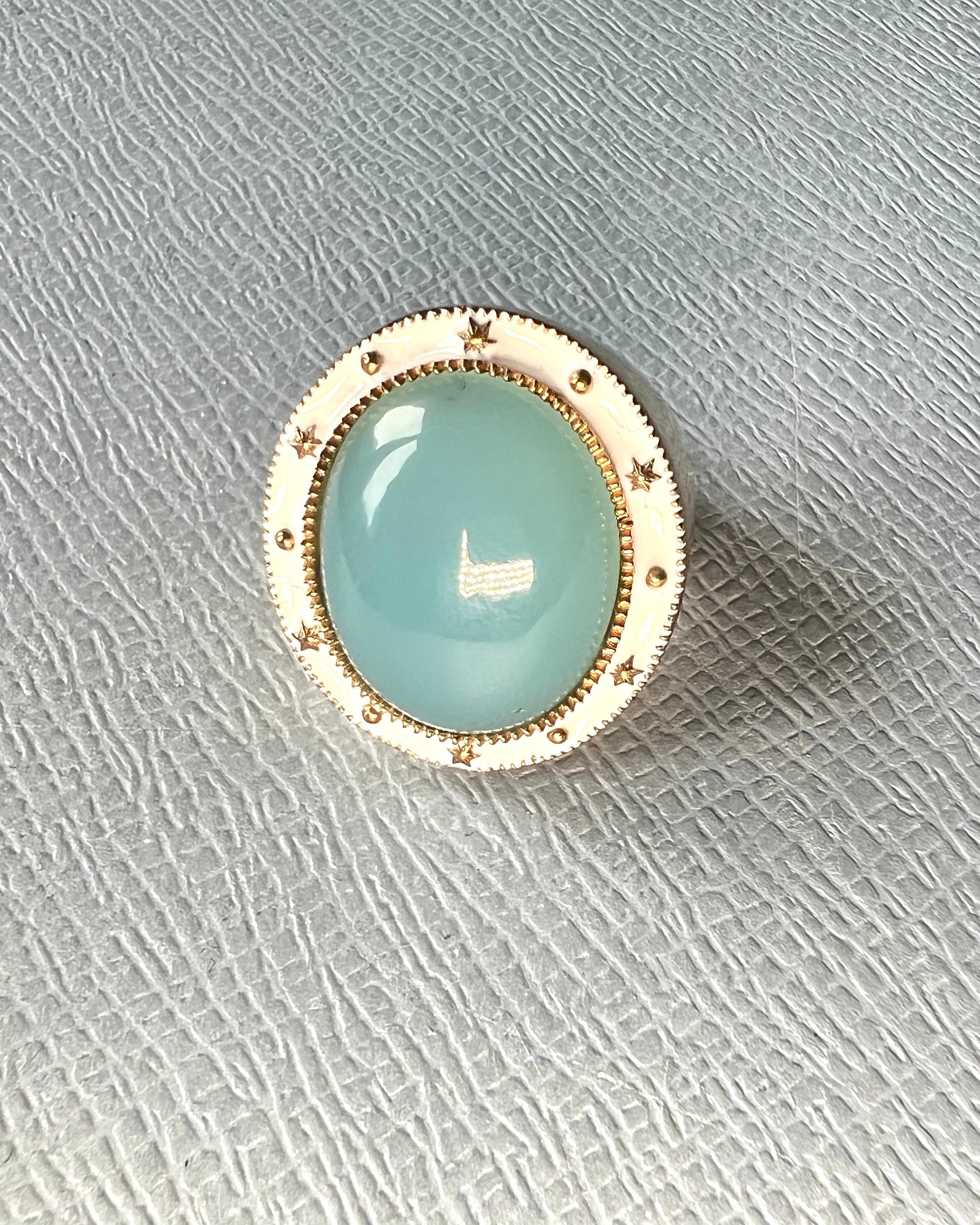 Bague cocktail en calcédoine bleue et émail blanc, plaquée or 14K
Designer : J DAUPHIN

Cette bague de cocktail fabriquée à la main présente un cabochon de calcédoine bleue lumineuse, serti dans un émail blanc lisse avec une finition plaquée or 14K