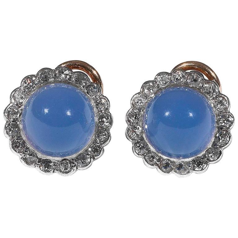 The round stud earrings with a sugarloaf shape blue chalcedony bordered by a line of round cut diamond.

Mounted in silver and gold

Pin and omega clip back

13 mm diameter

Weight: 5.1 gr 

