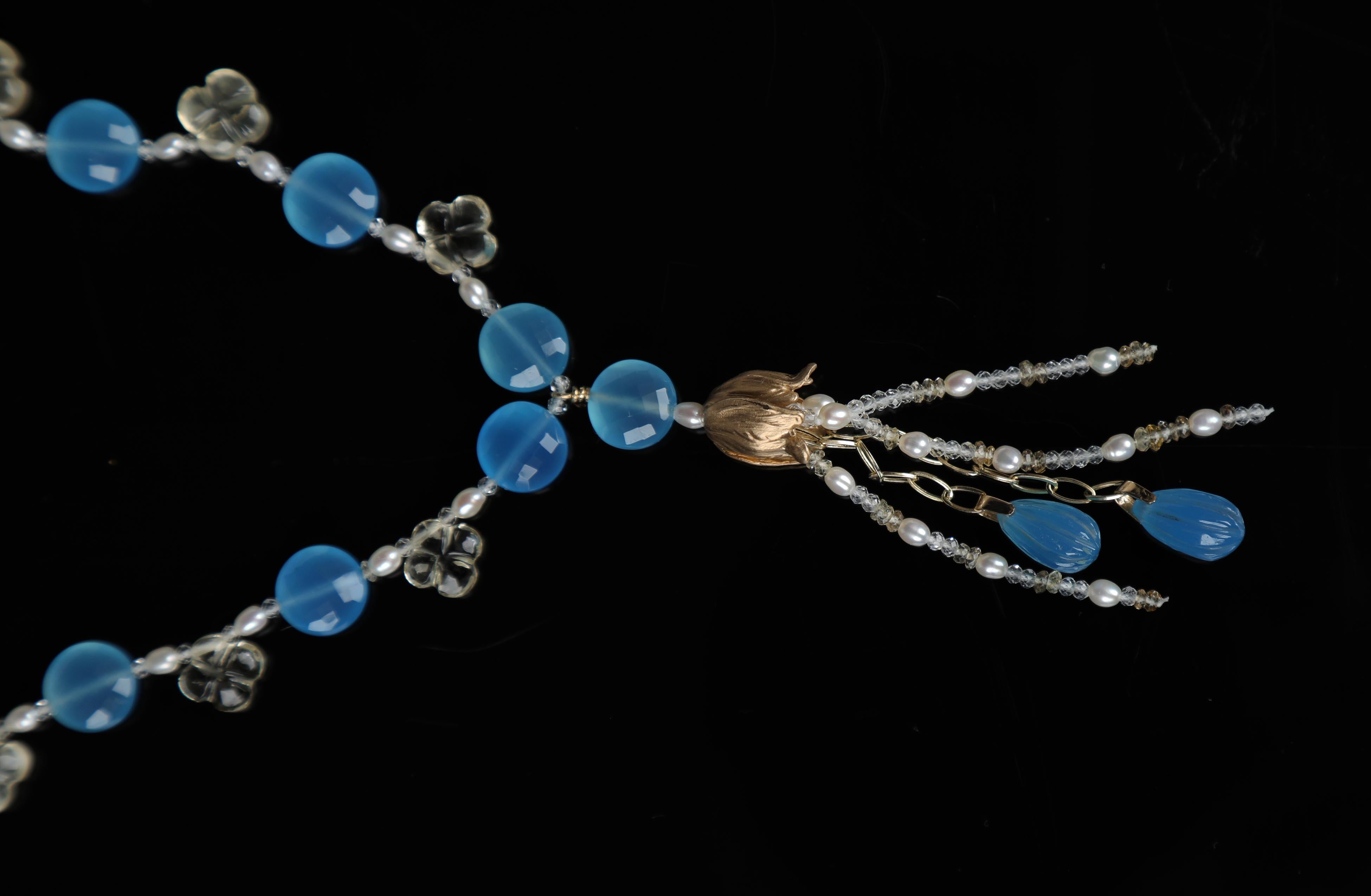 This blue chalcedony, carved scapolite, white topaz, pearl, and yellow gold necklace honors wild poppies native to the Himalayas.

