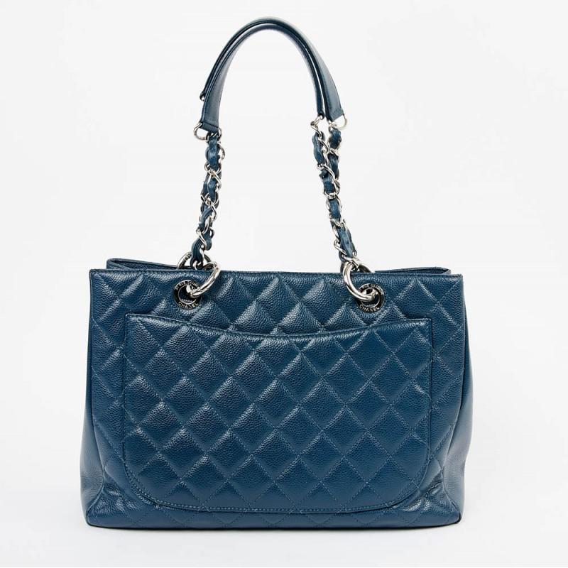 Big blue grained caviar leather tote from Maison CHANEL. The jewelry is in palladium silver metal. On the front of the bag a large CC is drawn in relief and on the back a large pocket plated. It is lined in gray satin with two storage place
