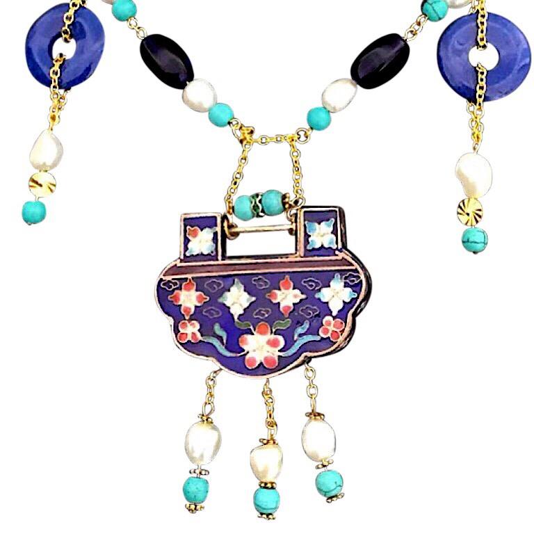 This necklace is my own design and features a Chinese cloisonné lock repurposed as a stunning pendant. The pendant is reversible with Chinese characters on the back. The necklace itself includes two lapis discs and real pearls with turquoise details