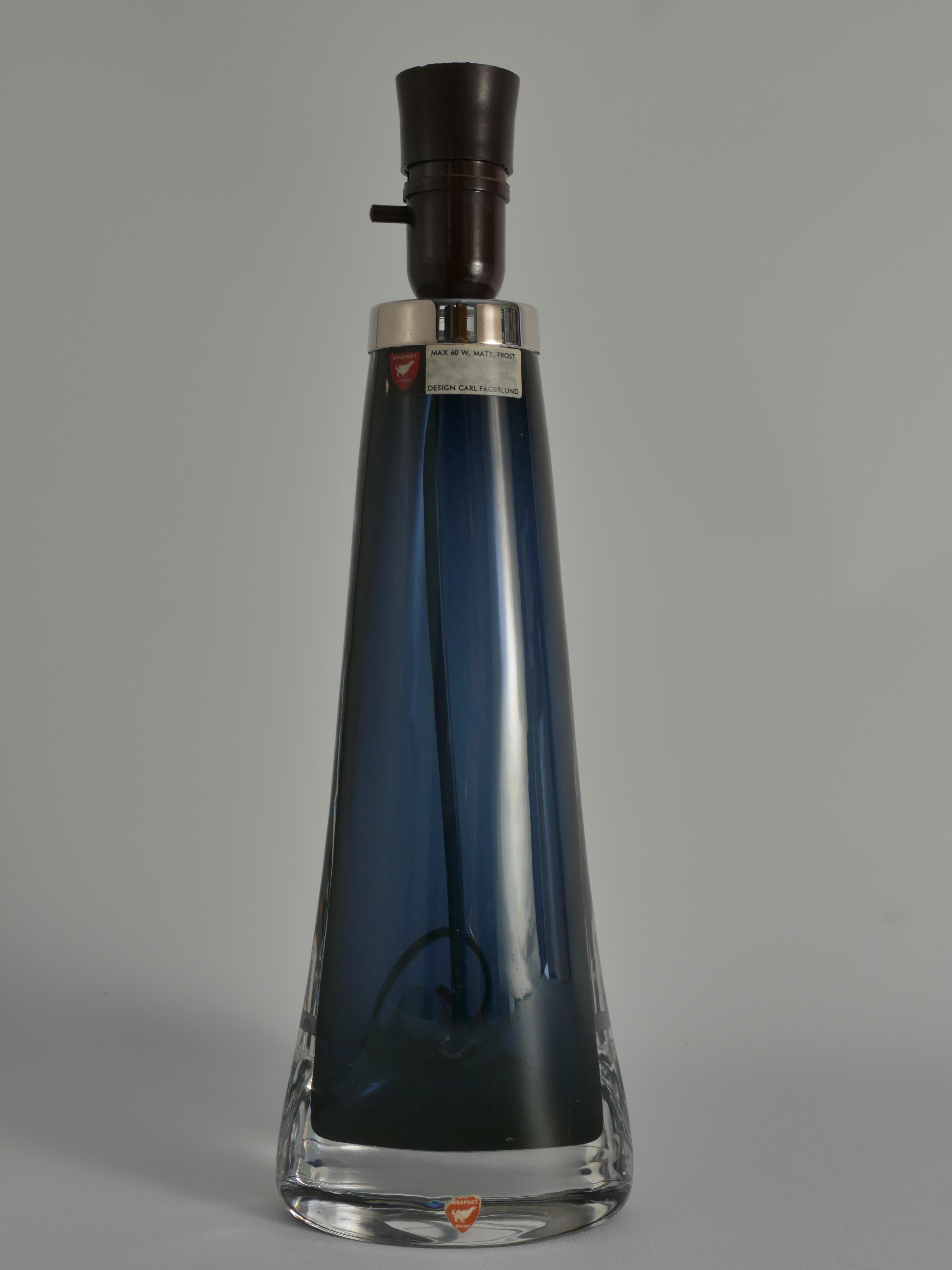 Cette exquise lampe de table moderne du milieu du siècle, modèle RD 1566 par Orrefors, met en valeur l'élégance intemporelle du design scandinave. Conçues par Carl Fagerlund et fabriquées à la main à partir de verre de cristal de haute qualité, ces