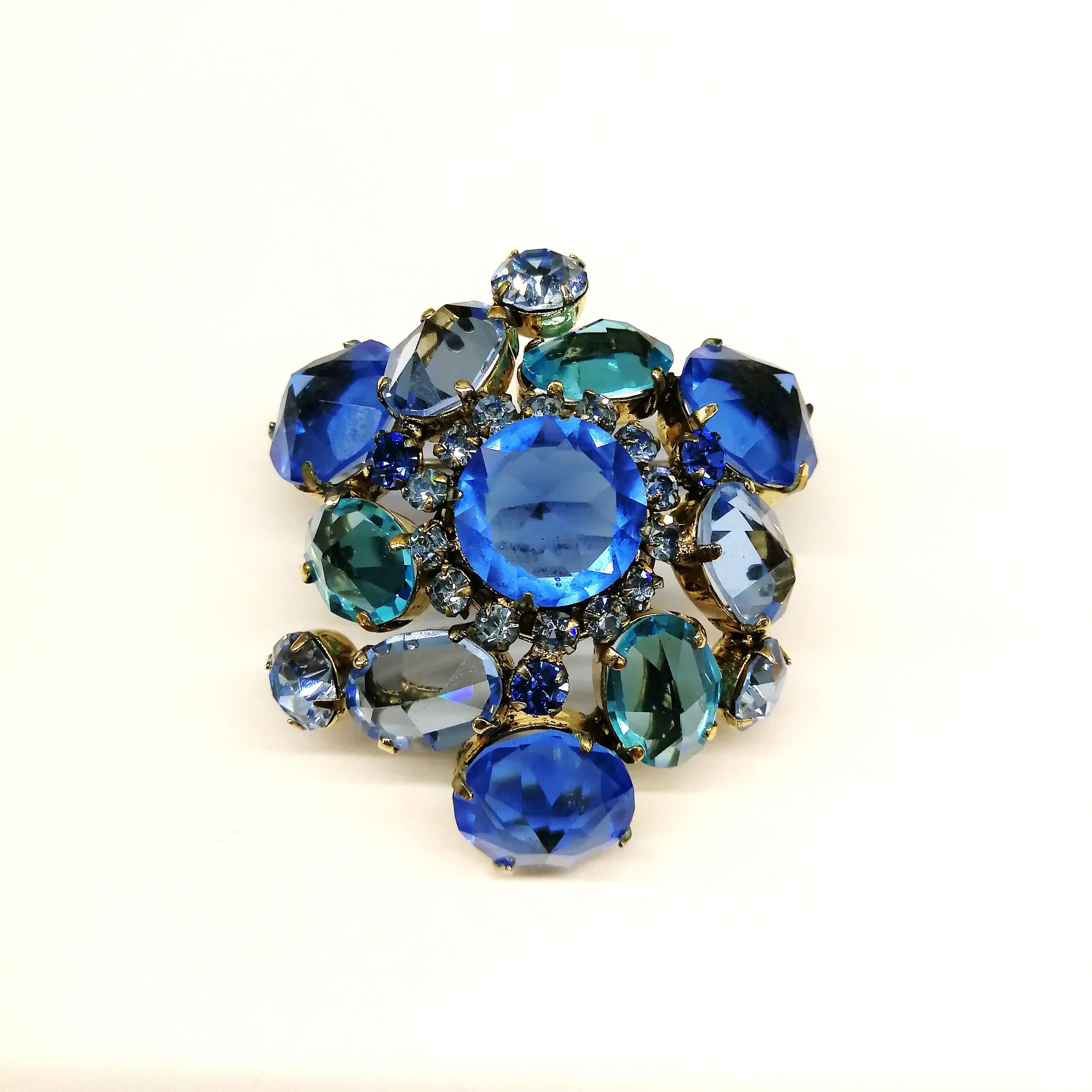 A beautiful, lush 'cluster' brooch, by Schreiner of New York, always a sign of glamour and style. Modest in size but rich and hue and design, varied shades of blues are set in gilded metal, an asymmetrical design, three dimensional,  higgledy
