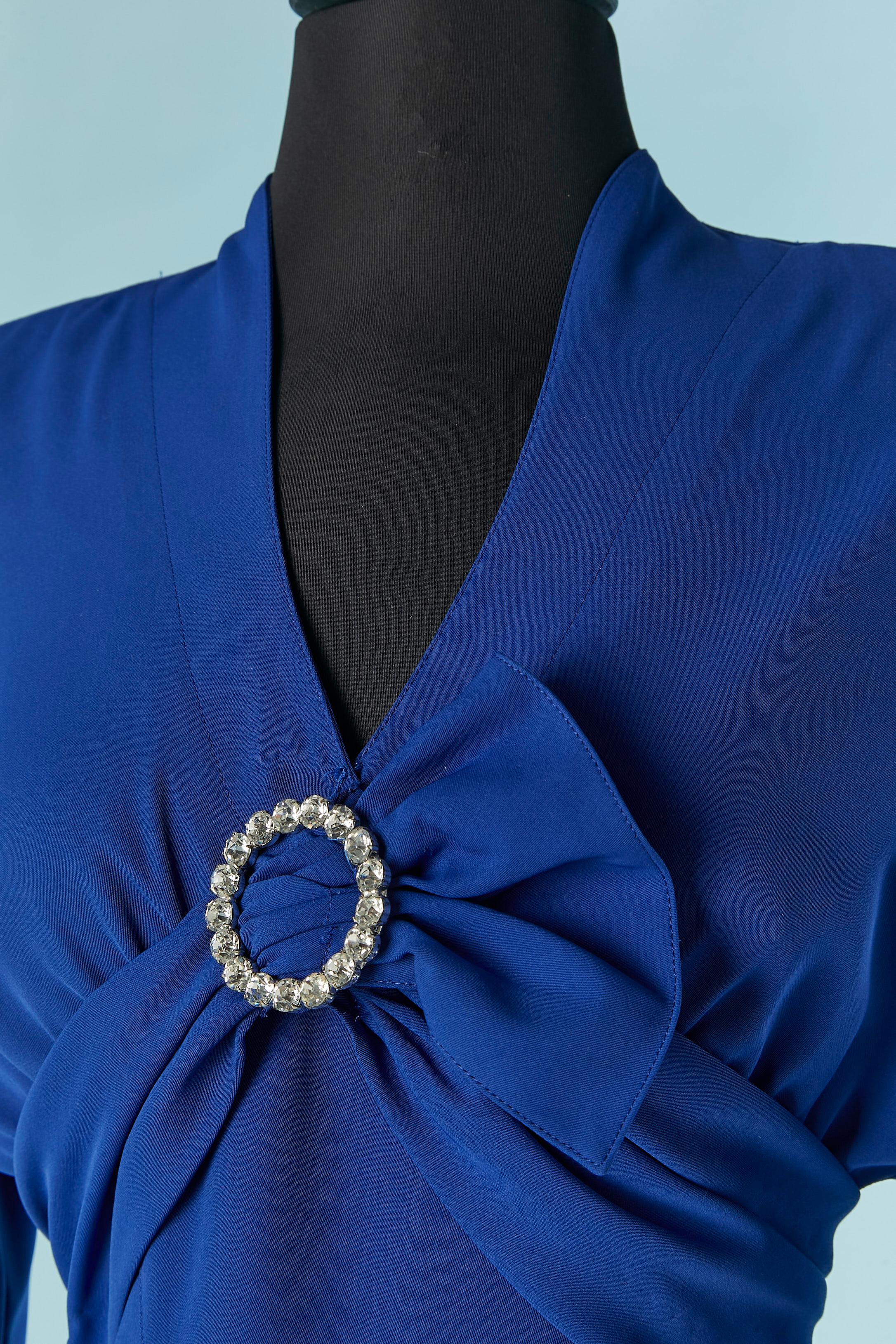 Robe de cocktail bleue avec broche en strass sur le buste. La composition du tissu a été coupée, le tissu principal est probablement du polyester et la doublure probablement de la rayonne ou de l'acétate. Travail de coupe sur le buste et fronces.