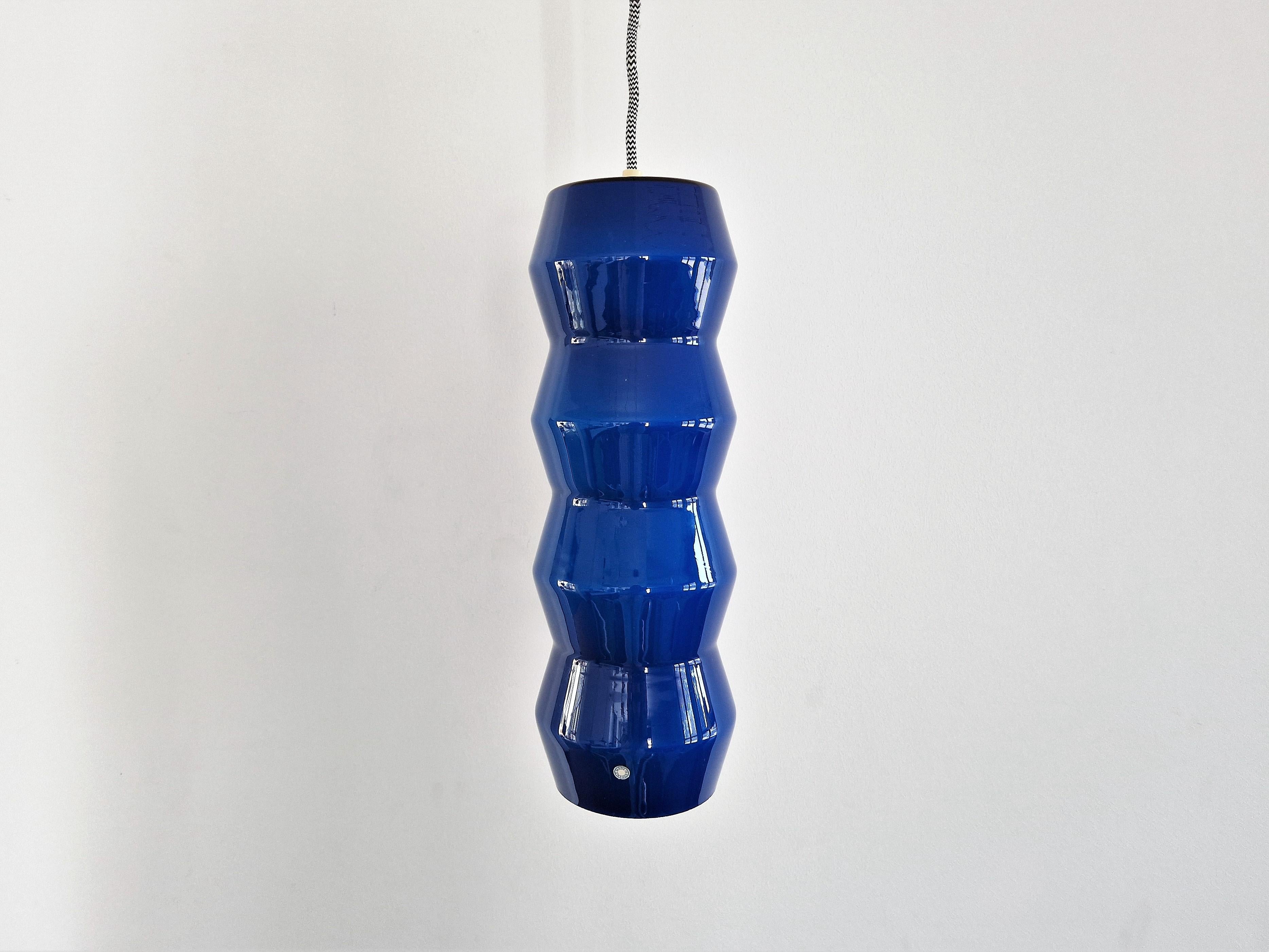 Cette étonnante lampe suspendue en verre façonné est documentée dans un catalogue de la société 'Indoor'. Il s'agissait de l'importateur et du distributeur de marques de luminaires telles que Vistosi, Venini et Arteluce aux Pays-Bas. Le catalogue de