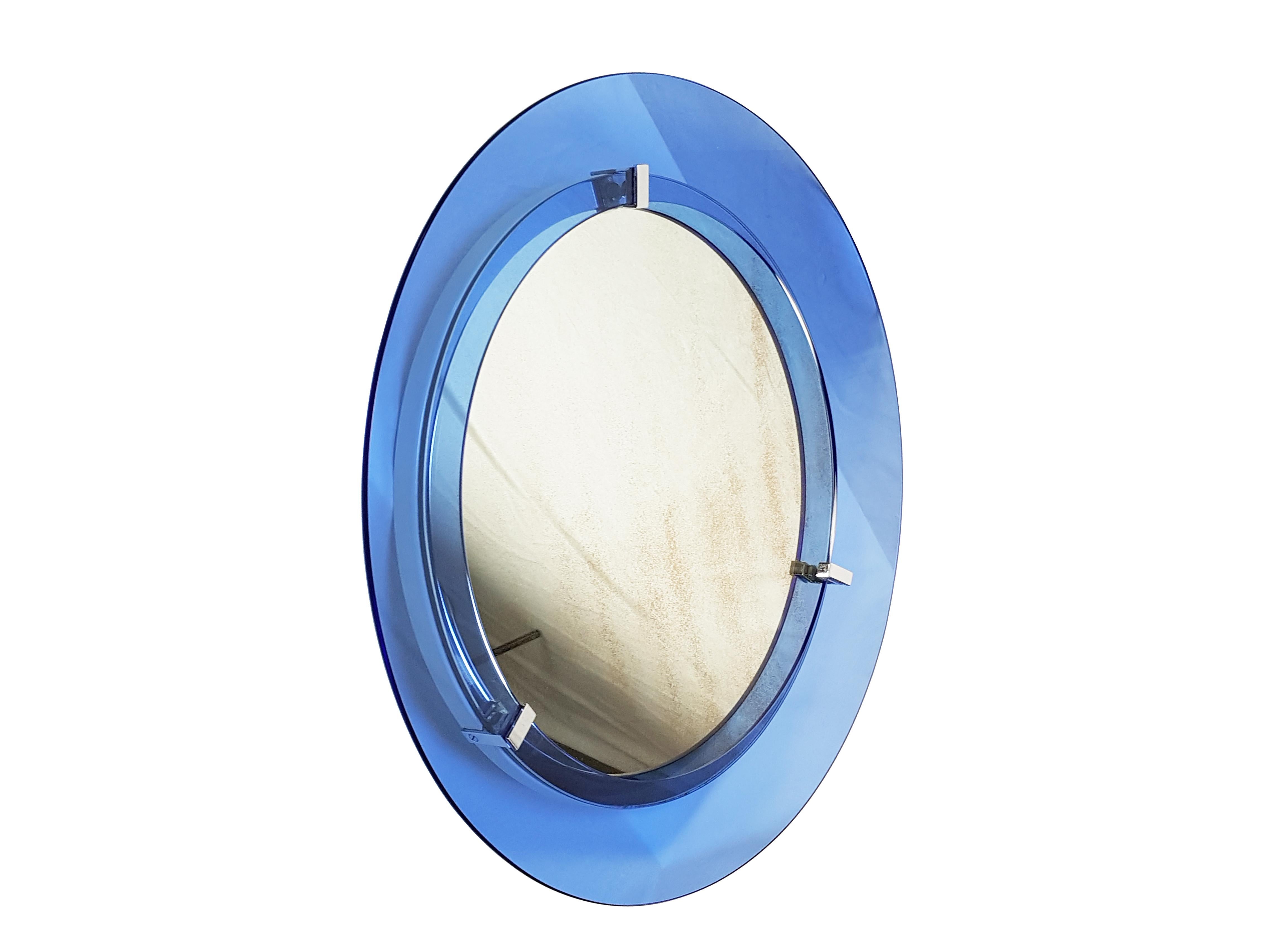 This beautiful and fine wall mirror is made from a convex blue glass frame connected to the main body through 4 chrome-plated metal supports. The frame and the white metal body remain in very good condition, the mirror shows visible signs of