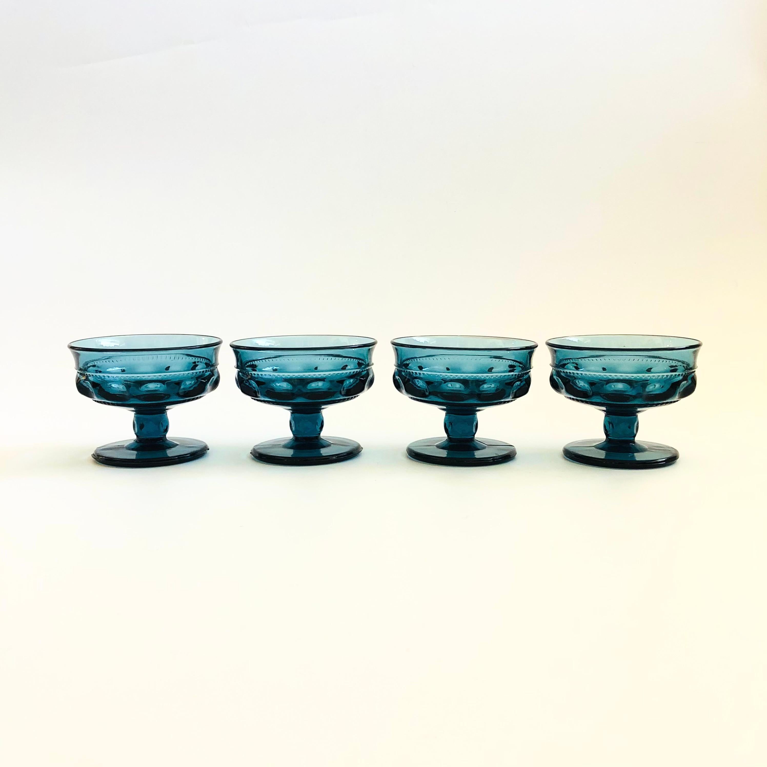 A set of 4 gorgeous coupe glasses with a lovely ornate design in blue glass. Made in the King's Crown pattern by Indiana Glass. Perfect for champagne, wine, or cocktails.

