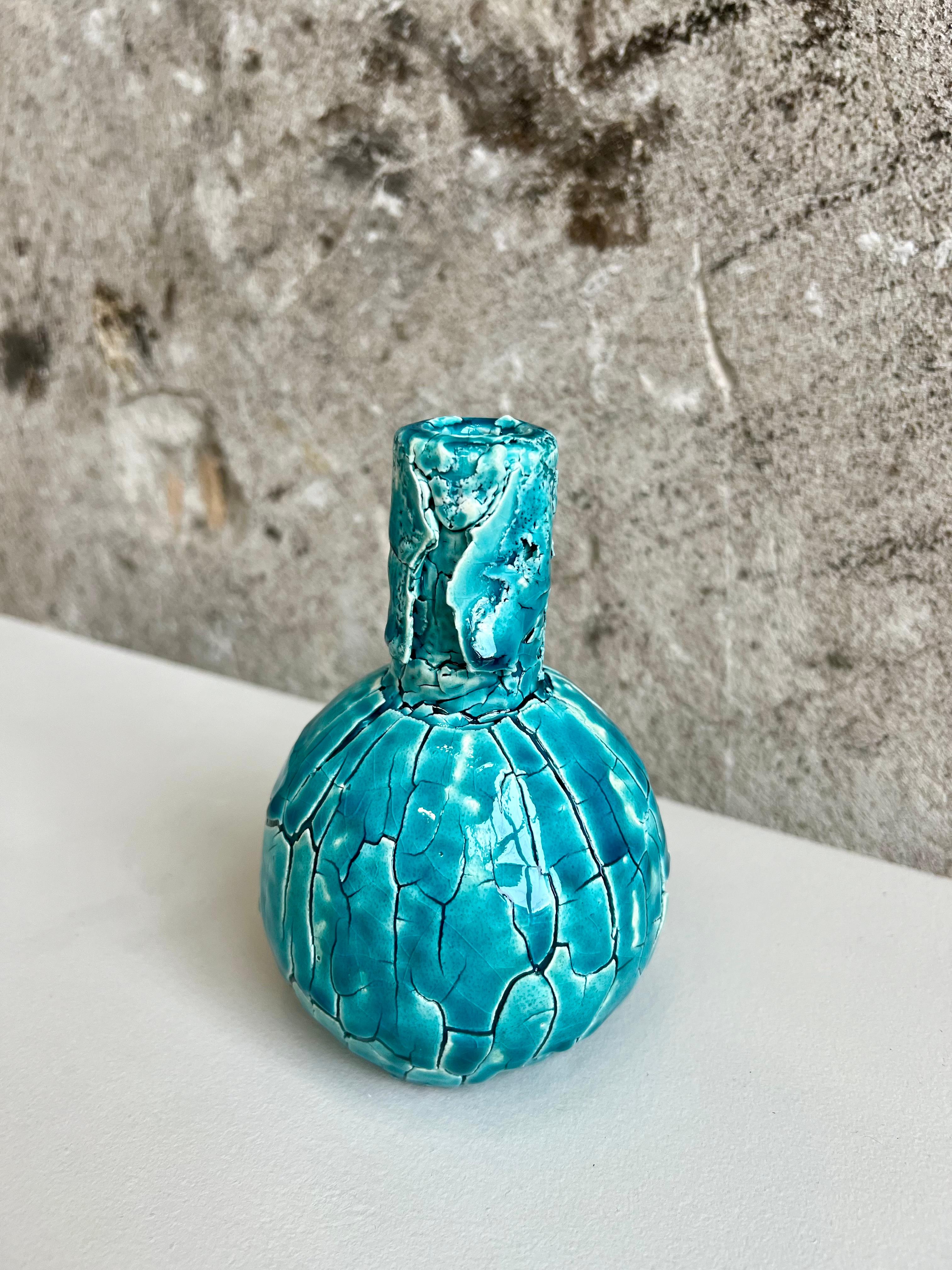 Small spherical vase with incredible crackle texture from handcrafting techniques.  In a beautiful blue and teal shade, this bud vase is functional and decorative. 

Teague’s work encompasses “everything under the sun,” he says, including