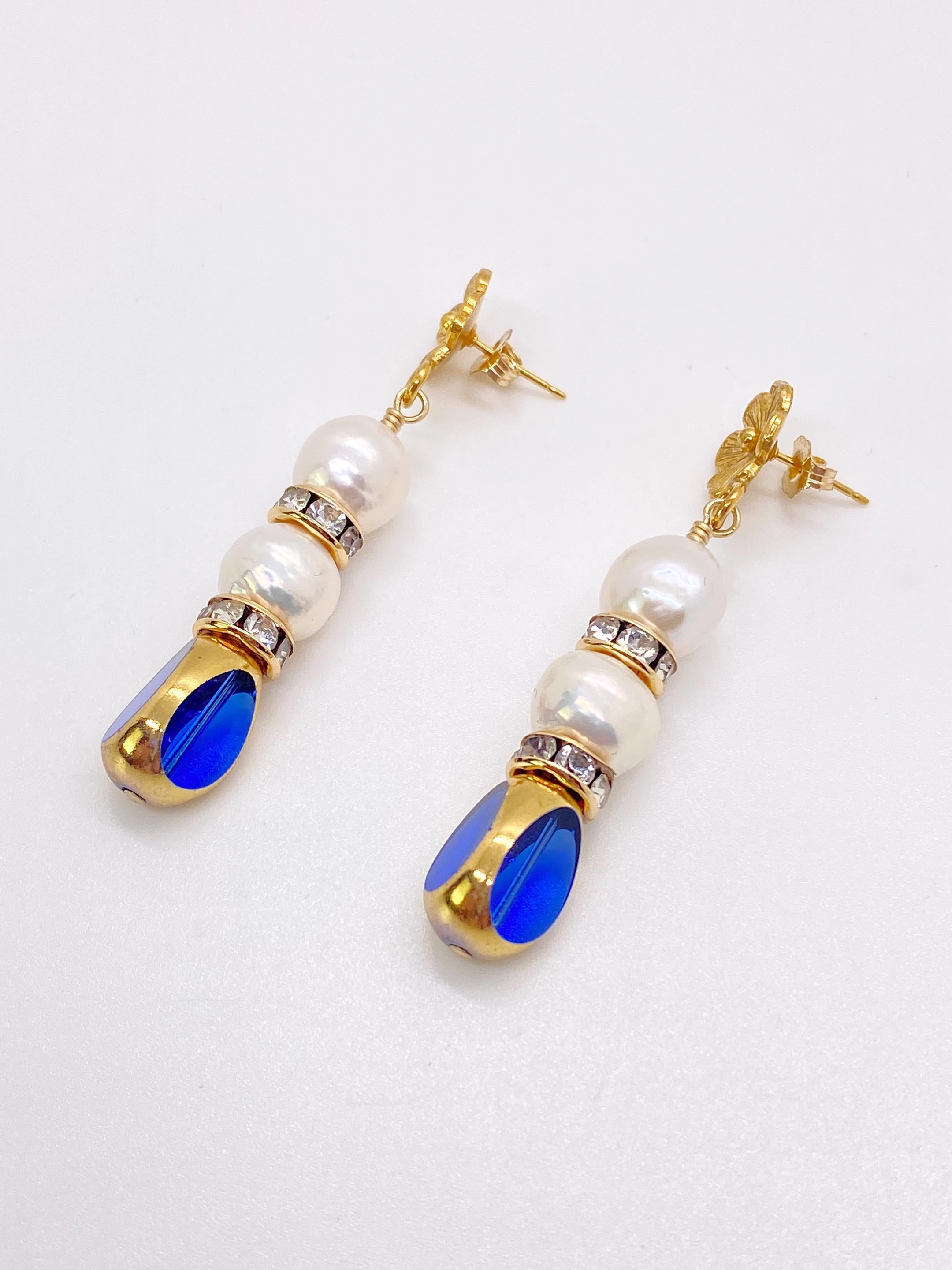 This is for a pair of earrings. Blue transparent vintage German glass beads edged with 24K gold are complimented with freshwater pearls. The earrings are finished with 24K gold plated floral earring post and 14K gold filled rhinestones spacers.

The