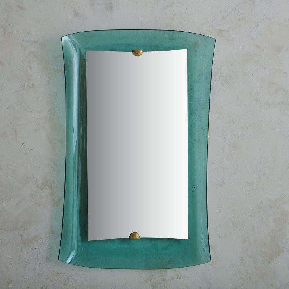 A 1950s Italian wall mirror attributed to Max Ingrand for Fontana Arte. This modernist piece features a concave crystal frame with curved edges in a striking blue hue. The frame supports a floating rectangular mirror, which is affixed to the frame