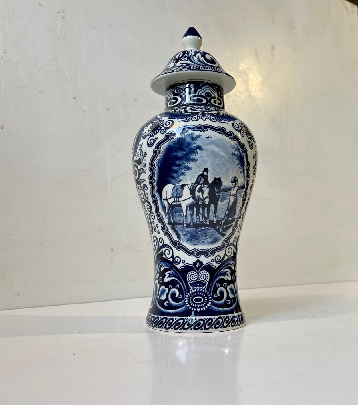Romantic blue Delft porcelain lidded vase or urn with idyllic horse scene. Decorated with flowers, leaves and ornaments derived from Dutch Colonial style. Measurements: H: 25 cm, Diameter: 11 cm.