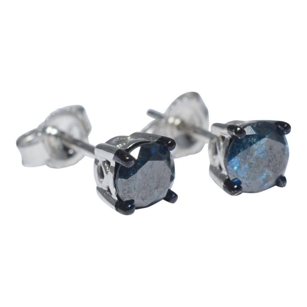 Contemporary teal blue solitaire diamond ear studs; the diamonds weigh 1ct total and are held by 4 blackened gold claws above a white gold cage setting.  Natural blue diamonds make millions of dollars, but fortunately technology offers a less