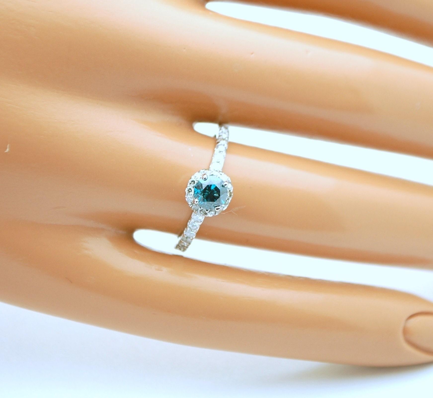Cute engagement ring for the lovers of blue, the enhanced blue diamond in the middle weighs 0.50 carats accompanied by halo of diamonds 0.40 carats in 14KT white gold. The diamonds are Si clarity and H-I in color. Ring is size 6 but can easily be