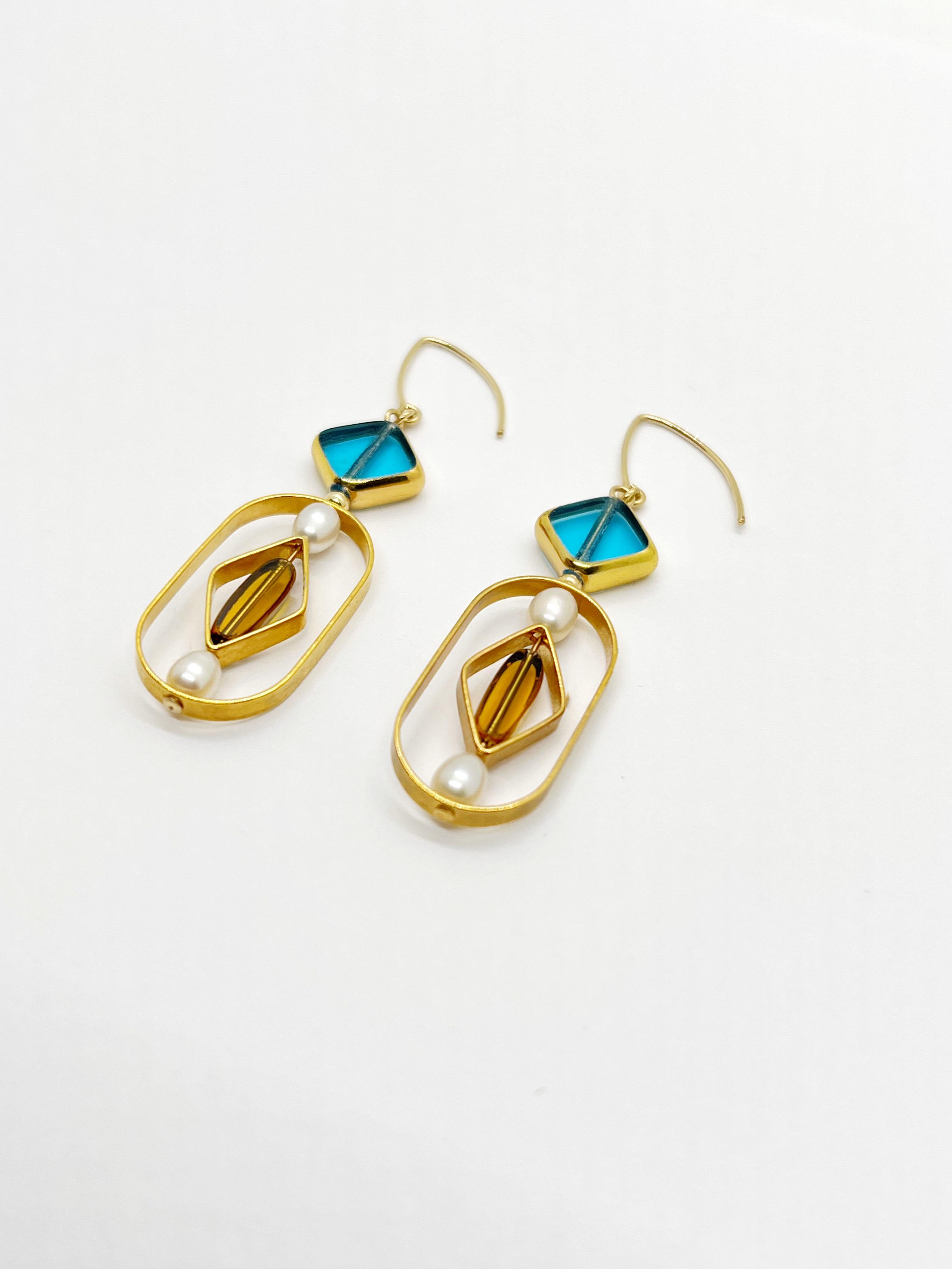 These earrings are light weight. It is composed of German Vintage Glass Beads that are edged with 24K gold. It is incorporated with oval freshwater pearls set in a geometric frame.

The vintage glass beads that is framed with 24K gold were hand