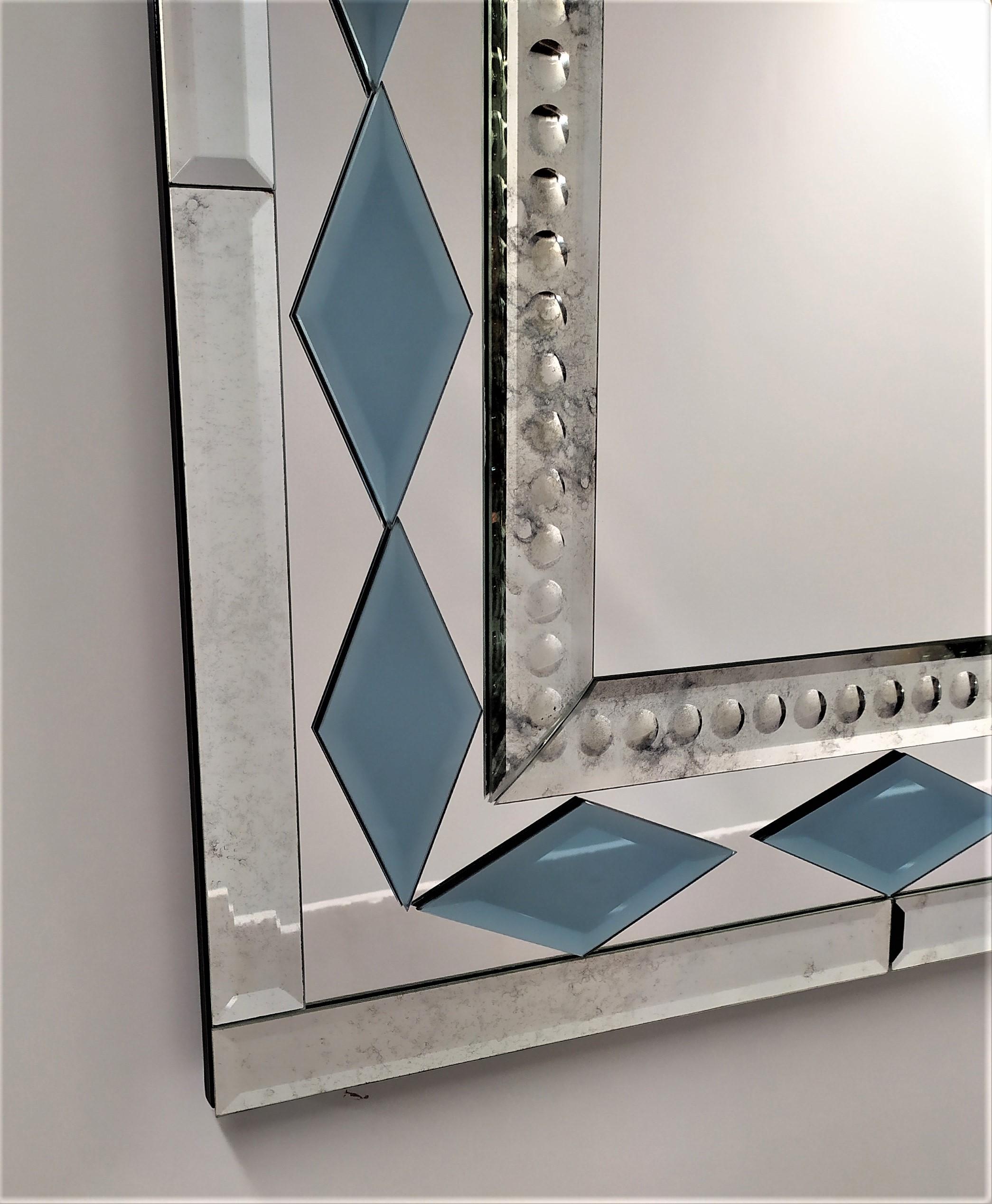Rectangular murano glass mirror, from the twenty-first century, composed of beveled, antiqued and bubbles engraved bands by hand, with the insert of the blue crystal rhombuses faceted like diamonds all handmade, produced in a limited mirror made by