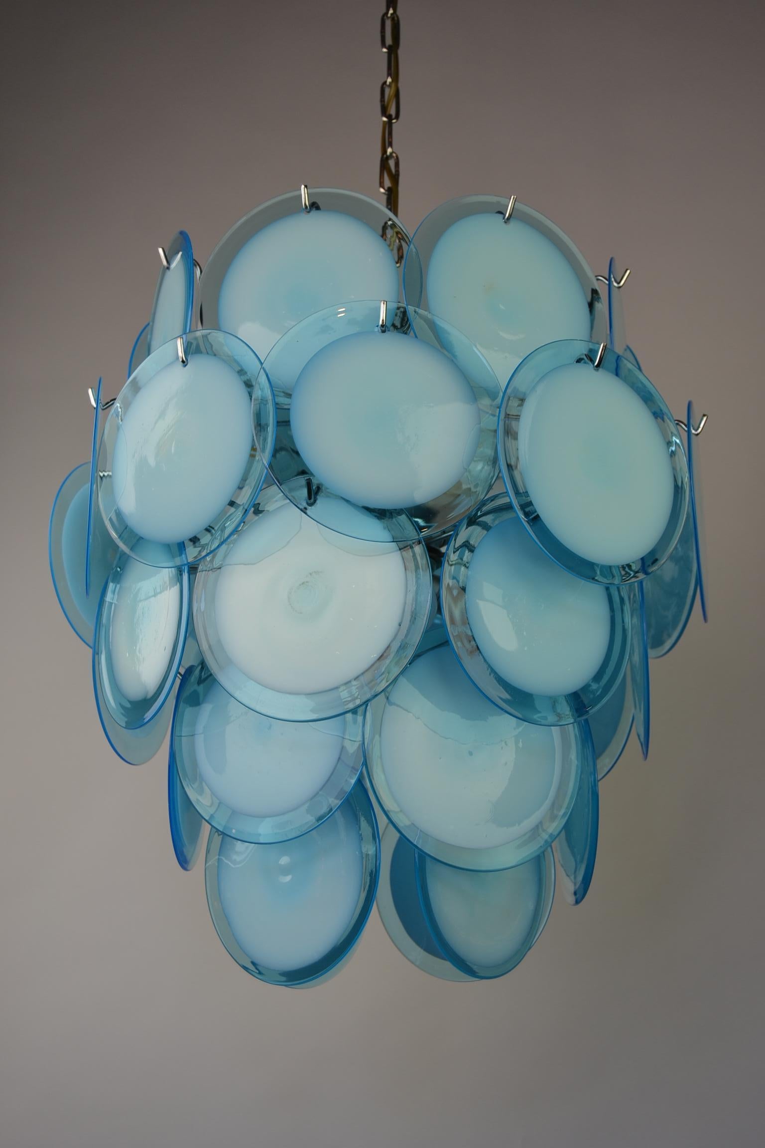 Blue Disc Murano Glass Chandelier. 
This large Italian Chandelier has a chrome frame on a chain,  eight light bulbs with E14 fitting and 36 handblown blue glass discs. 
The 36 discs are placed in 5 layers. 
The chrome of this large modern chandelier
