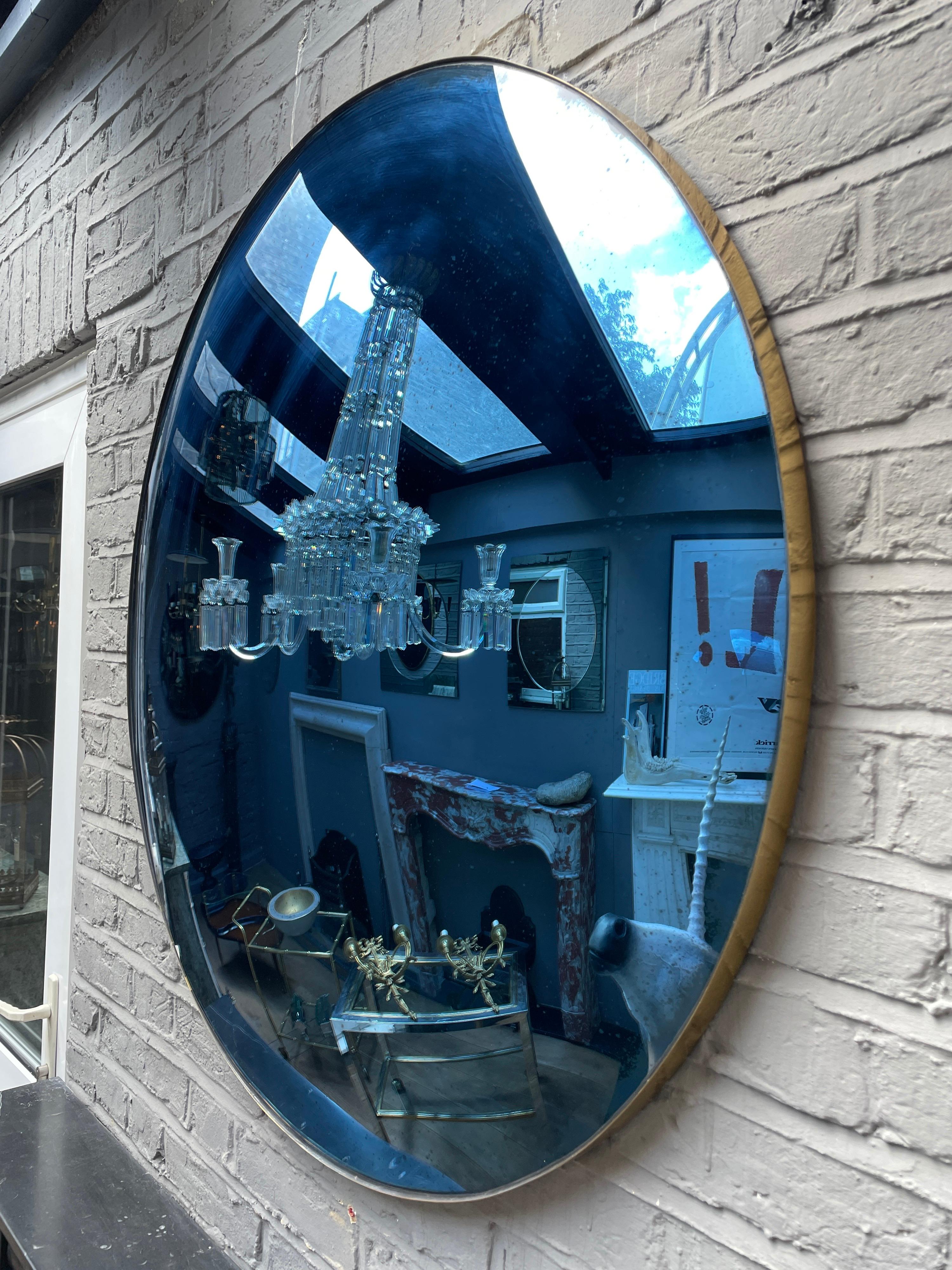 A large circular convex mirror in distressed blue glass within a brass banded frame. Contemporary.