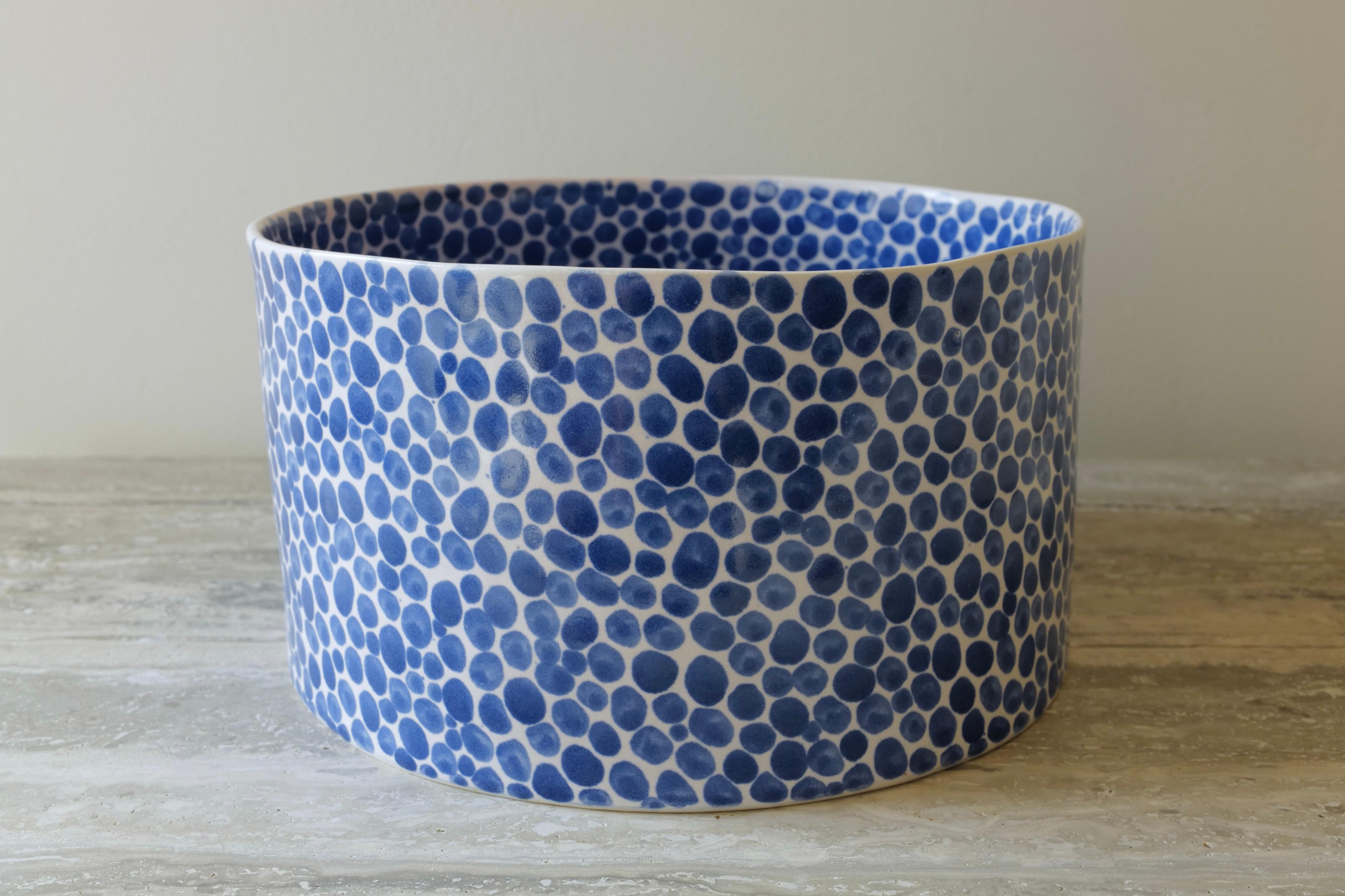 This multi-functional ceramic bowl is perfect for fruits or vegetables as well as for flowers as a wide, deep vase. Hand-cast in porcelain and once bisque fired, each dot is hand-painted with a traditional cobalt blue glaze. An unconventional