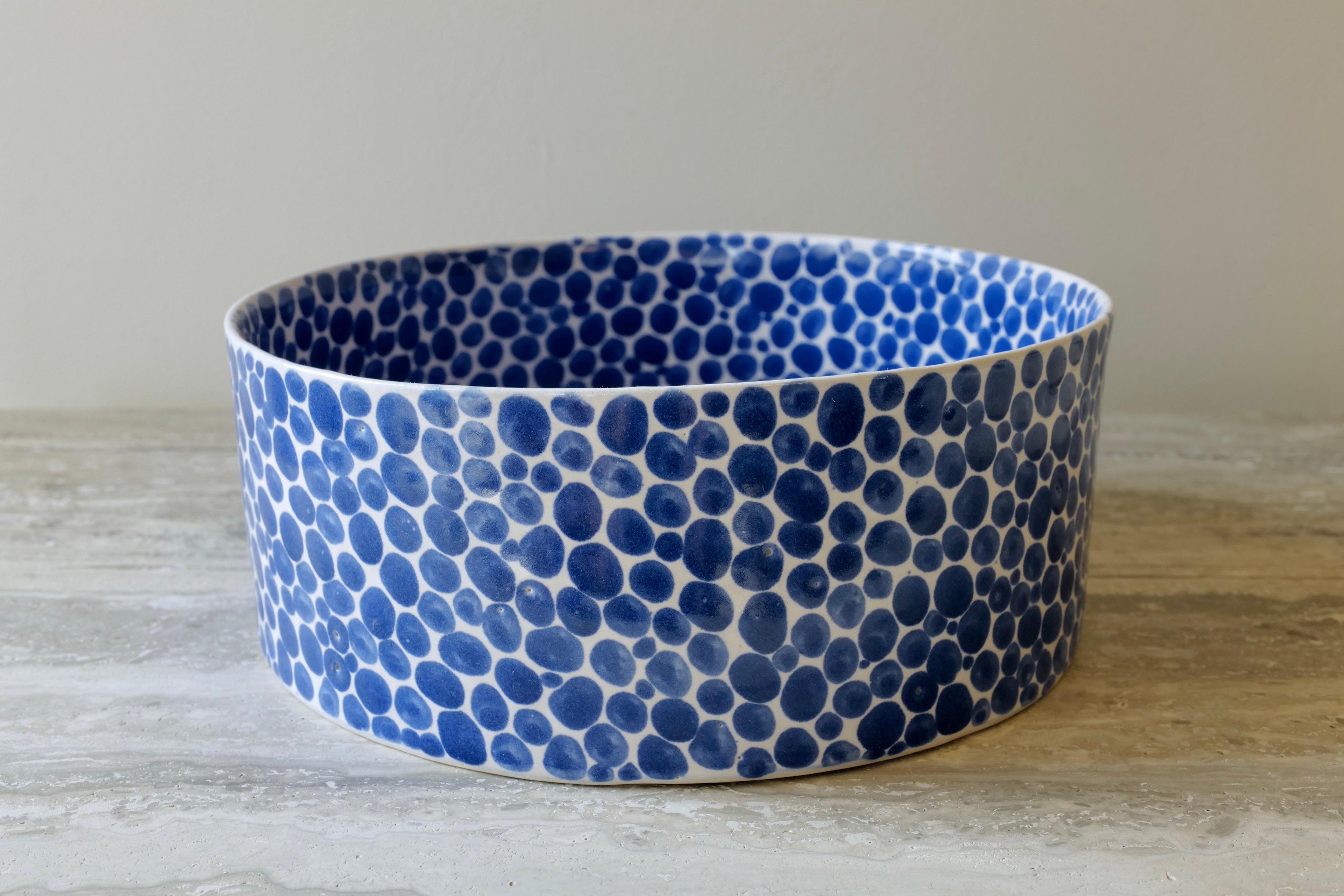 This multi-functional bowl is perfect for fruits or vegetables or for serving food. Hand-cast in porcelain and once bisque fired, each dot is hand-painted with traditional cobalt blue glaze. An unconventional layered glazing technique, developed by