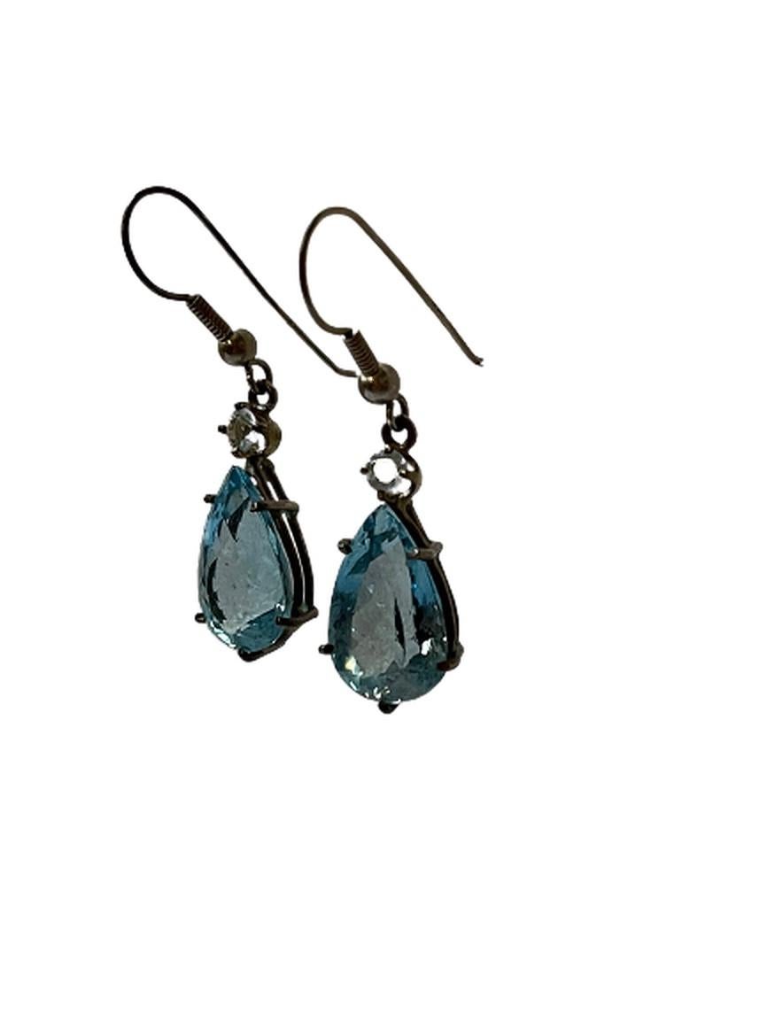 This is a pair of earrings made from sterling silver and a blue topaz-type of stone, which has been heavily faceted. They are a wonderful aqua blue that glistens in the light reminiscent of peridot or the ocean on a perfect summer day.

The