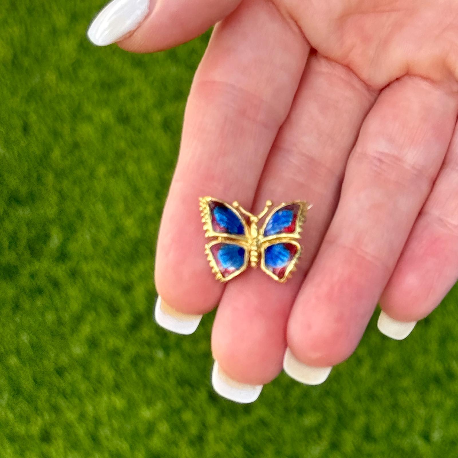 Butterfly enamel pin beautifully crafted in 18 karat yellow gold. The brooch features blue and red enamel for colorful wings with textured gold design. The brooch measures 15 x 20mm. Weight: 3.0 grams.