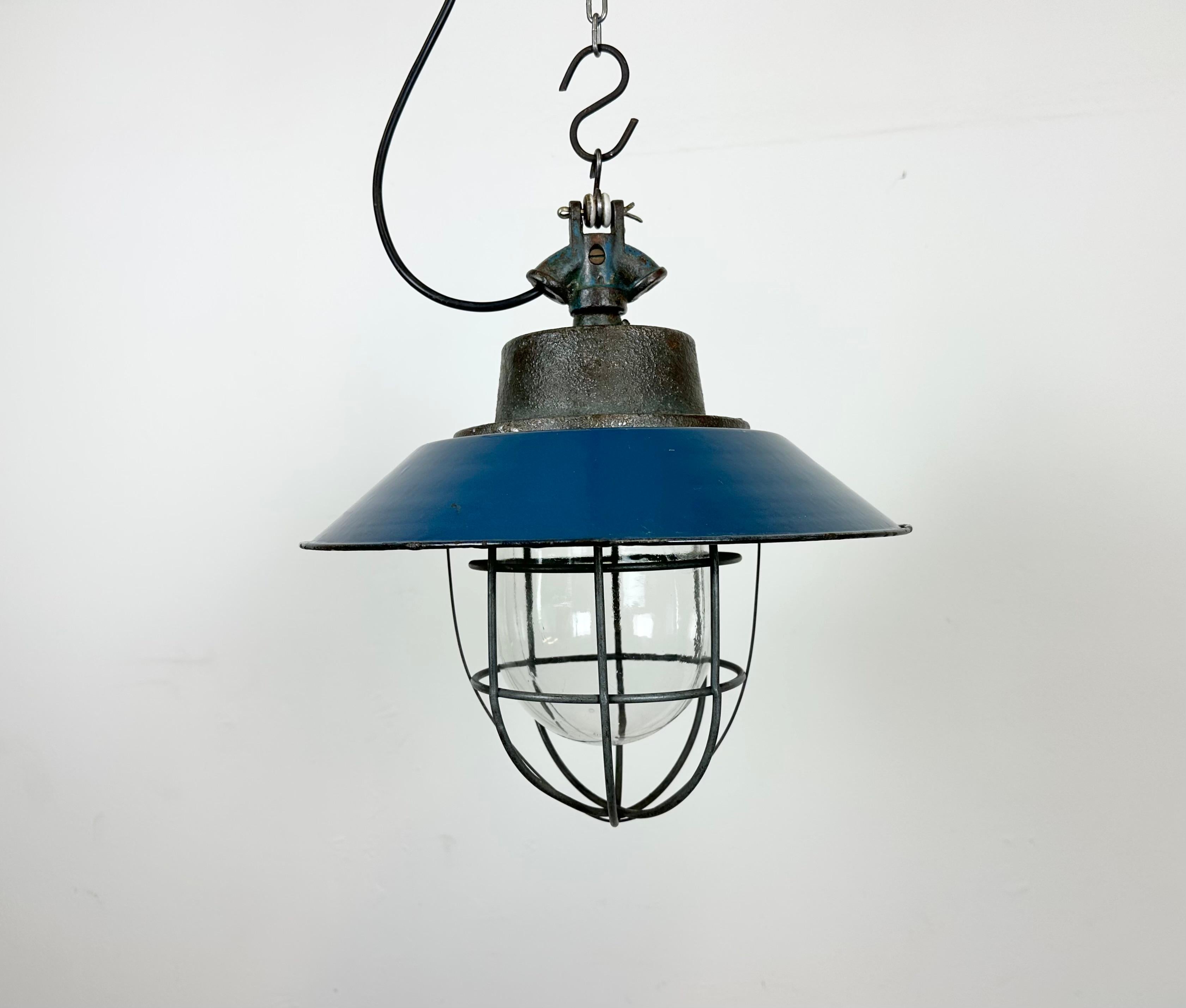 Industrial hanging lamp manufactured in Poland during the 1960s. It features a blue enamel shade with white enamel interior, a cast iron top,a clear glass cover and iron grid. The porcelain socket requires E 27 lightbulbs .New wire. The weight of