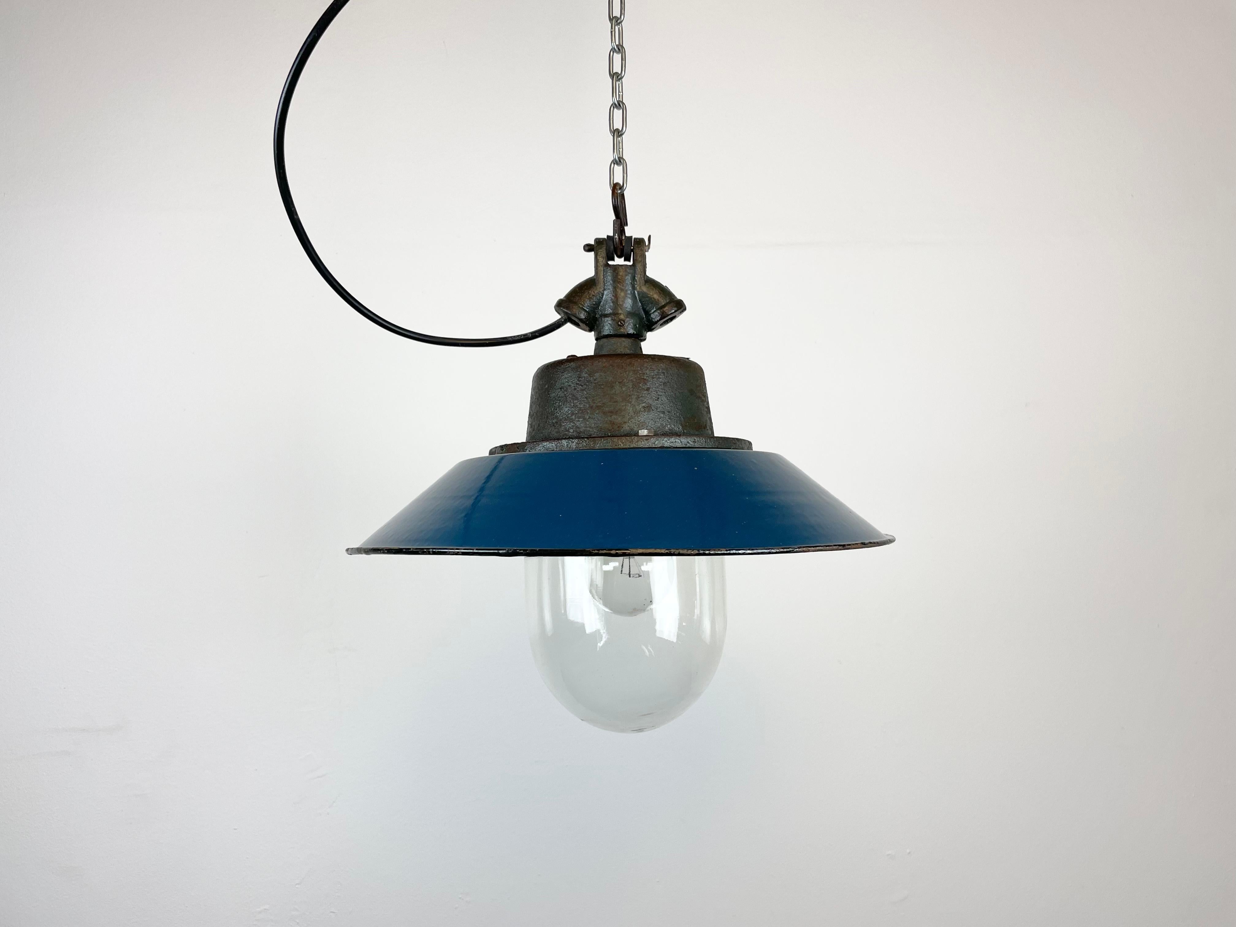Industrial hanging lamp manufactured in Poland during the 1960s. It features a blue enamel shade, white enamel interior, cast iron top and clear glass cover. Porcelain socket for E 27 light bulbs and new wire. The weight of the lamp is 3 kg.