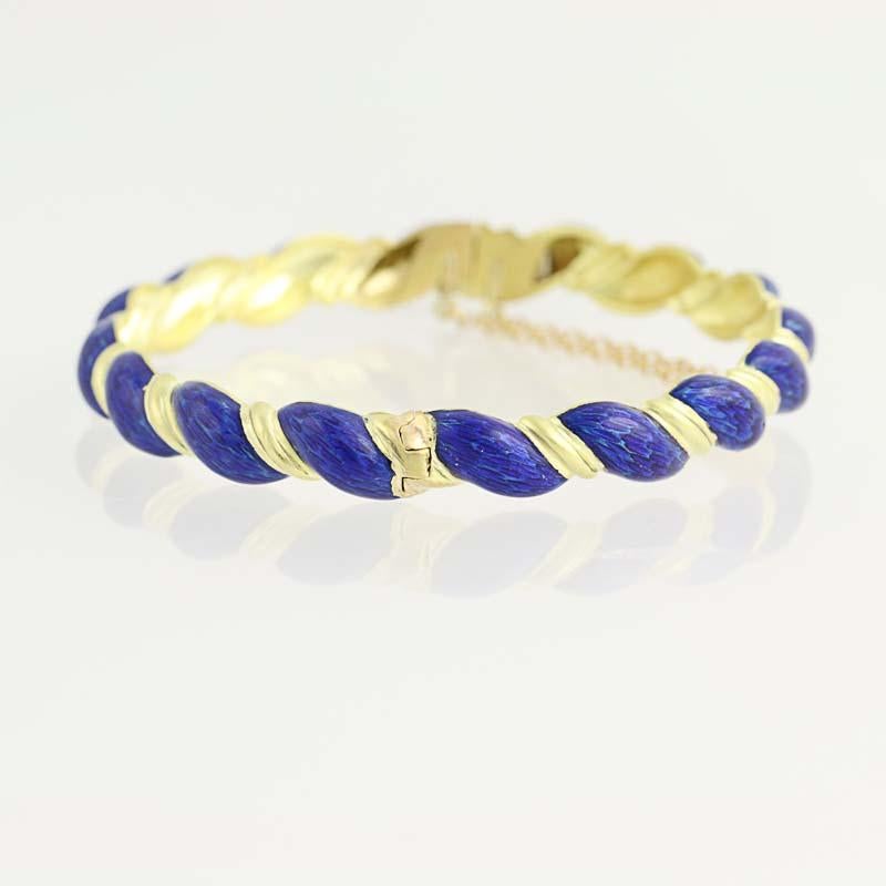 Elegance meets Style in this gorgeous bracelet! Fashioned in high purity 18k yellow gold, this cuff-style piece features a rope design with strands of textured gold wrapping around blue- enameled strands. Please note that the royal-blue enamel is in