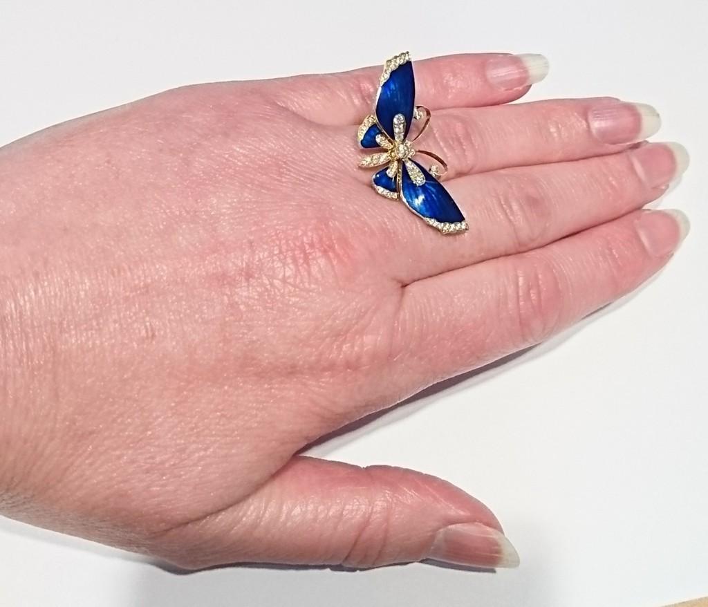 A dark blue guilloche enamel butterfly ring, set with 0.39ct of round brilliant-cut diamonds to the wings, head and abdomen, mounted in gold, with a plain shank.

The butterfly measures approximately 37mm x 17mm.