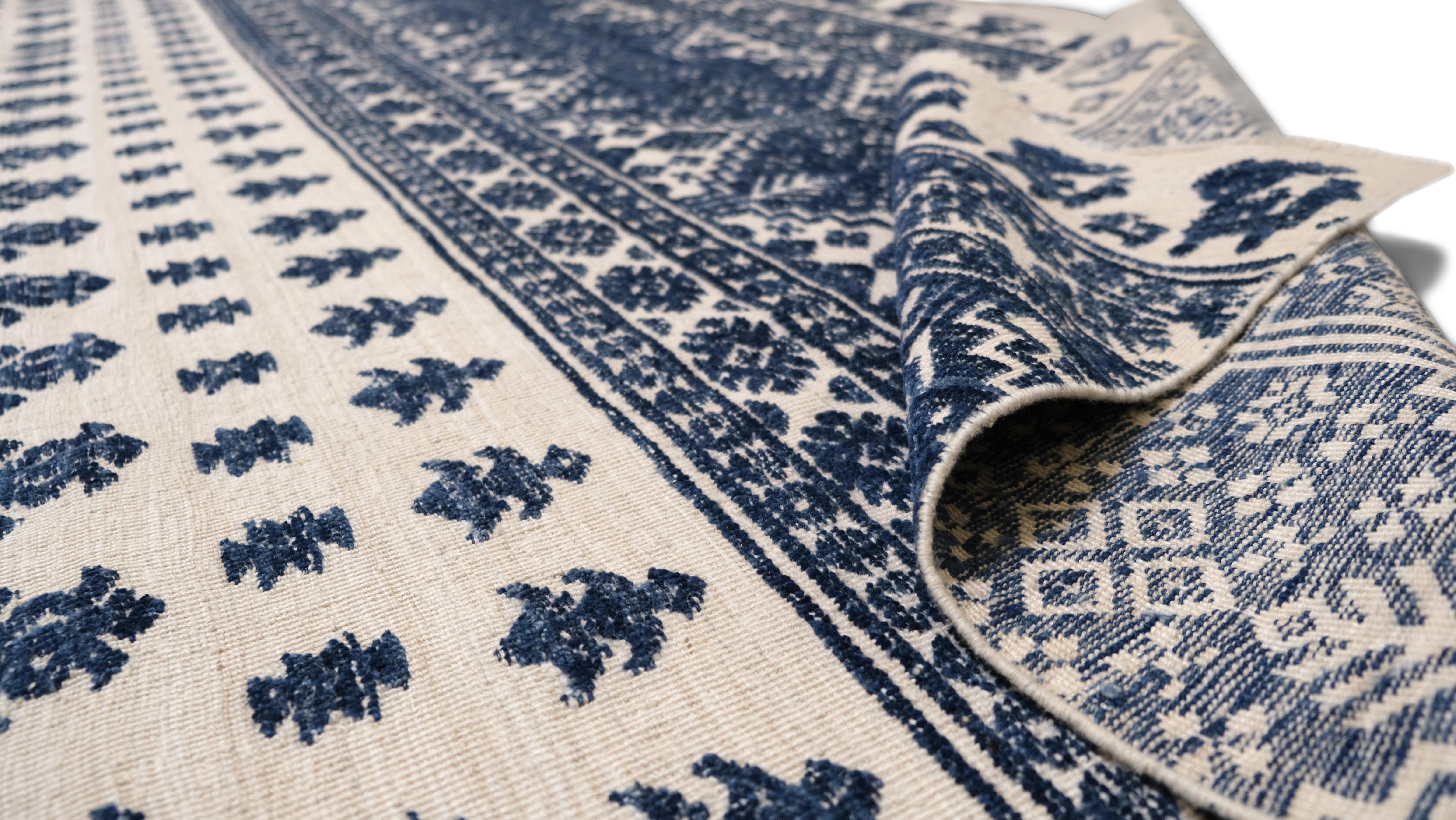 Enhance your interior with this exquisite hand-knotted wool rug, featuring a striking blue floral and geometric pattern on a Ivory cream background. The intricate detailing of the floral motifs, combined with the symmetrical geometric borders,