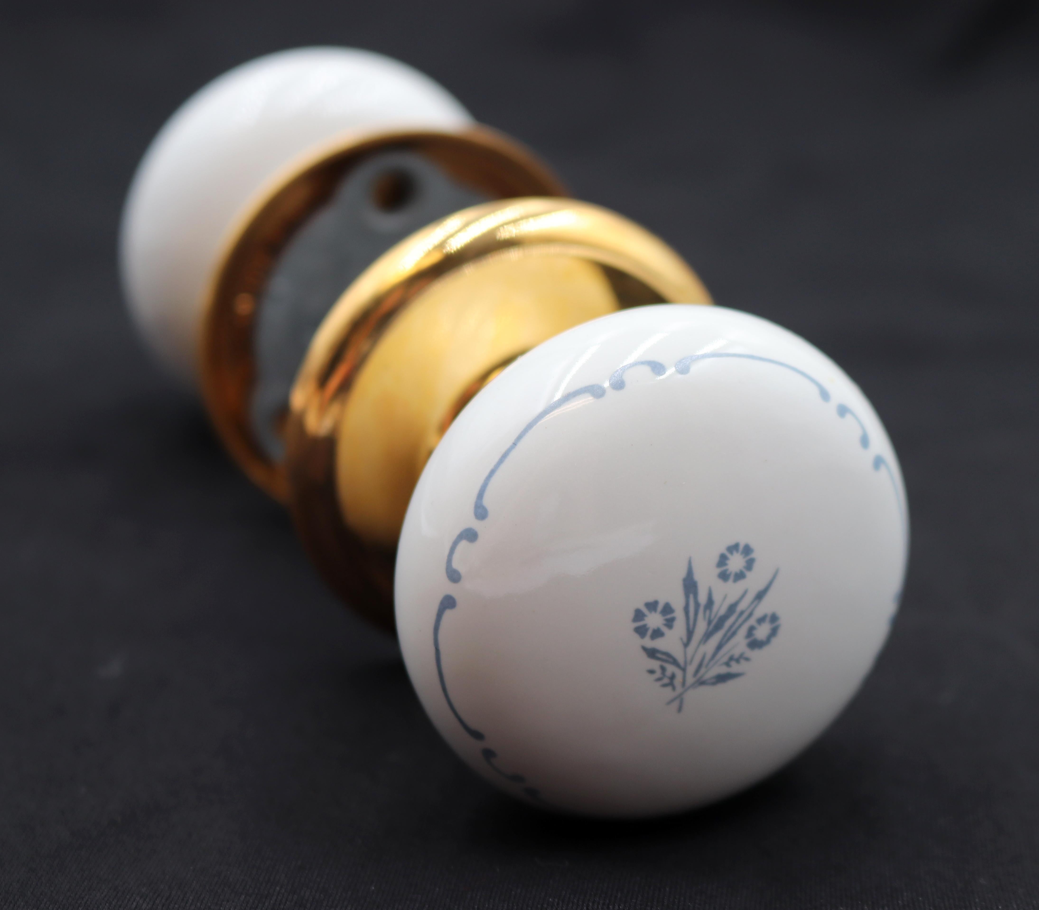 Este juego de picaportes de paso incluye dos picaportes de cerámica blanca con un motivo floral azul y blanco y dos rosetas de latón pulido. Fabricado por Gainsborough. Los tornillos de montaje originales no están disponibles. Su precio es de dos