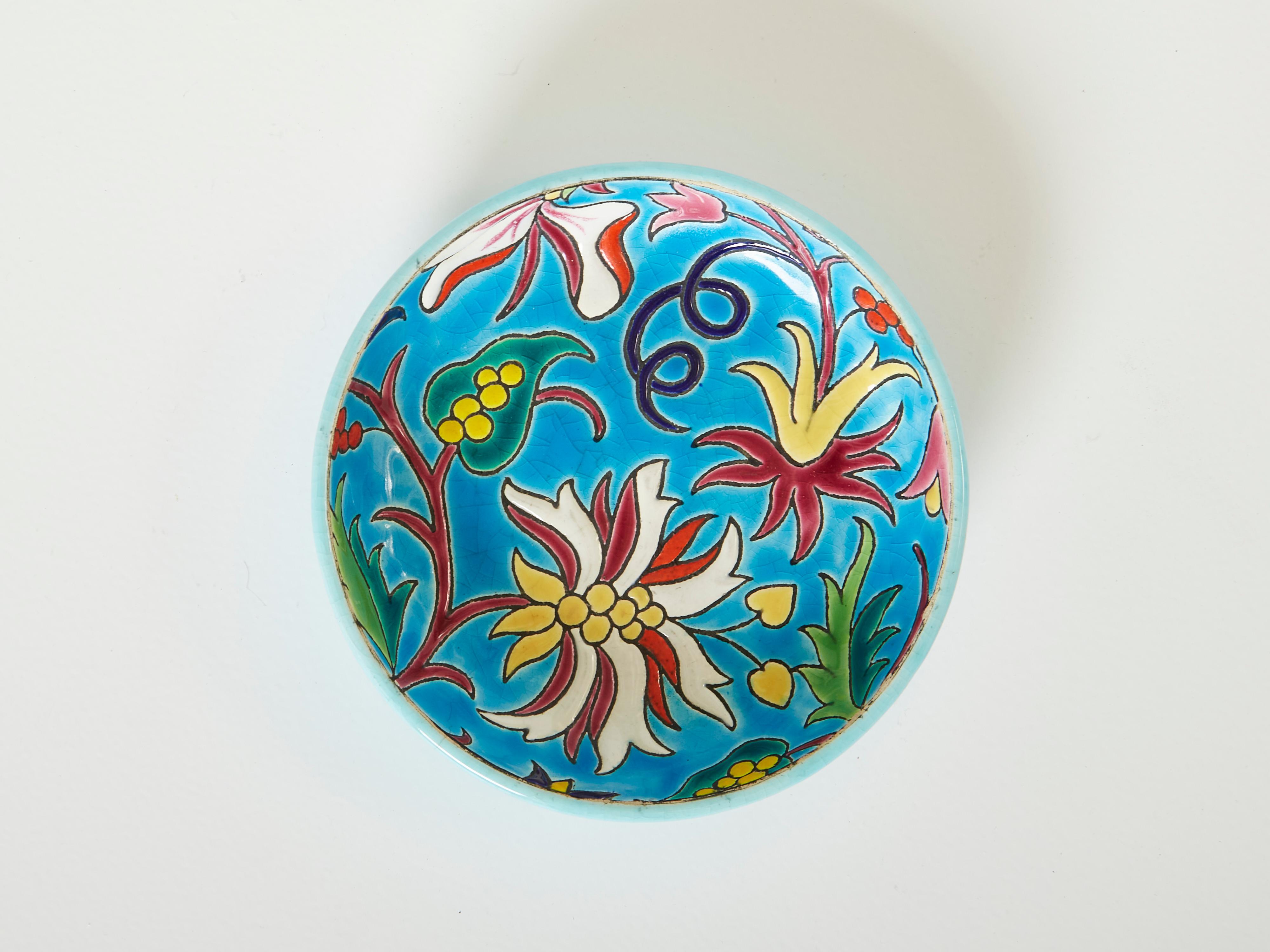 Bunte runde Keramikschale im Art déco-Stil von Faïenceries et Emaux de Longwy aus der Zeit um 1950. Diese türkisblaue Schale ist rundum mit schönen Blumen und der für Longwy typischen Craquelé-Glasur verziert. Die Manufaktur Longwy kann auf eine