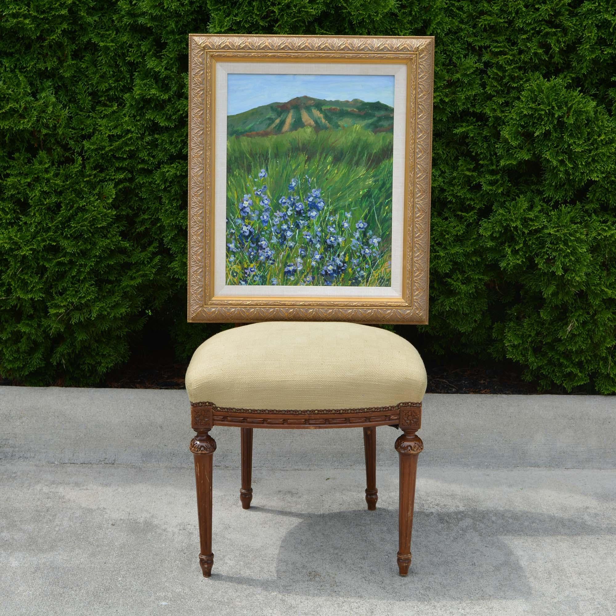 The blue flowers are the focal point of the landscape in this painting. There is a hillside that climbs toward the sky in the background, setting the tone of this lovely countryside. Soft green tones with romantic blues. The canvas is signed L Melle